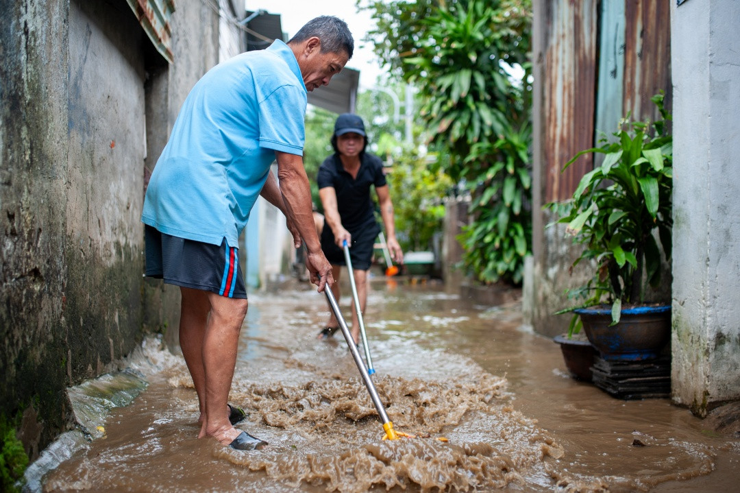 Hì hục đẩy bùn trong hẻm ra ngoài đường lớn, ông Ngọc Cứ, 54 tuổi cho biết: “Tranh thủ ngớt mưa, mình đẩy bớt bùn non ra ngoài, không thôi nước rút khó vệ sinh với bây giờ đi lại dễ bị trơn té. Năm trước là bùn hắn đóng trên tường luôn, nhưng mà năm nay chưa đến mức đó”.