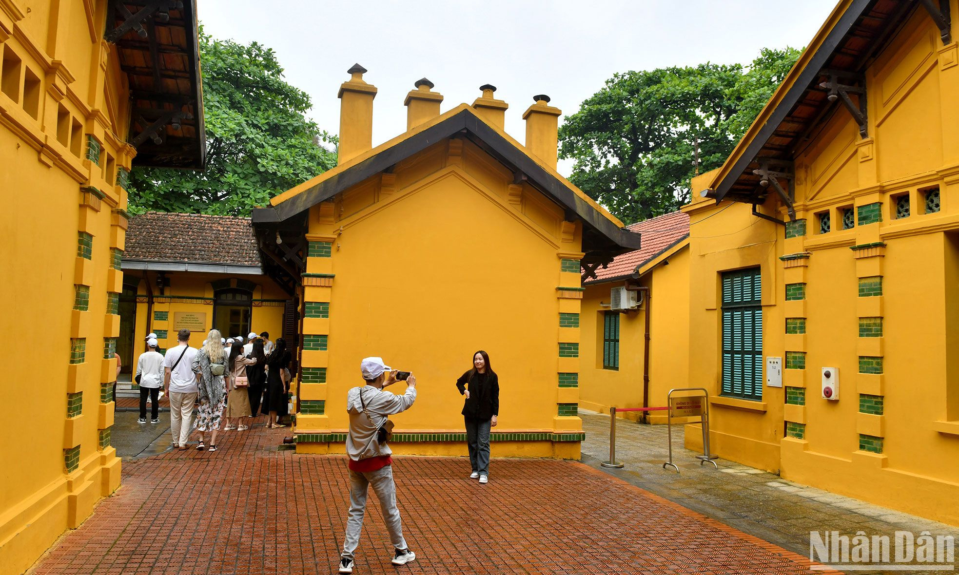 Du khách tham quan những dãy nhà màu vàng có kiến trúc đặc sắc trong Khu di tích.