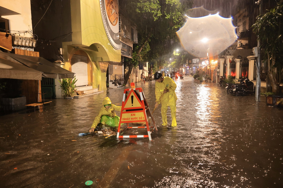 Công nhân Xí nghiệp thoát nước số 1 Hà Nội tích cực khơi thông dòng chảy đoạn ngập sâu trên phố Nguyễn Gia Thiều, quận Hoàn Kiếm. (Ảnh: Hoàng Hiếu/TTXVN)