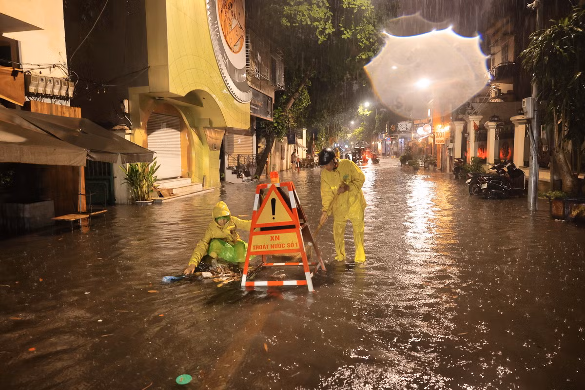Công nhân Xí nghiệp thoát nước số 1 Hà Nội tích cực khơi thông dòng chảy đoạn ngập sâu trên phố Nguyễn Gia Thiều, quận Hoàn Kiếm. (Ảnh: Hoàng Hiếu/TTXVN)