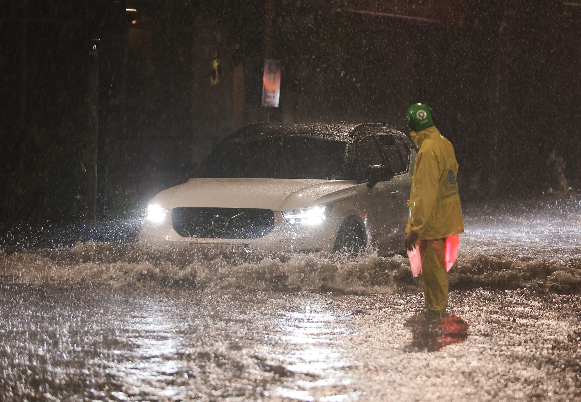 Công nhân Công ty thoát nước Hà Nội có mặt để hướng dẫn người dân đi qua điểm ngập ngã tư Phan Bội Châu - Lý Thường Kiệt, quận Hoàn Kiếm. (Ảnh: Hoàng Hiếu/TTXVN)