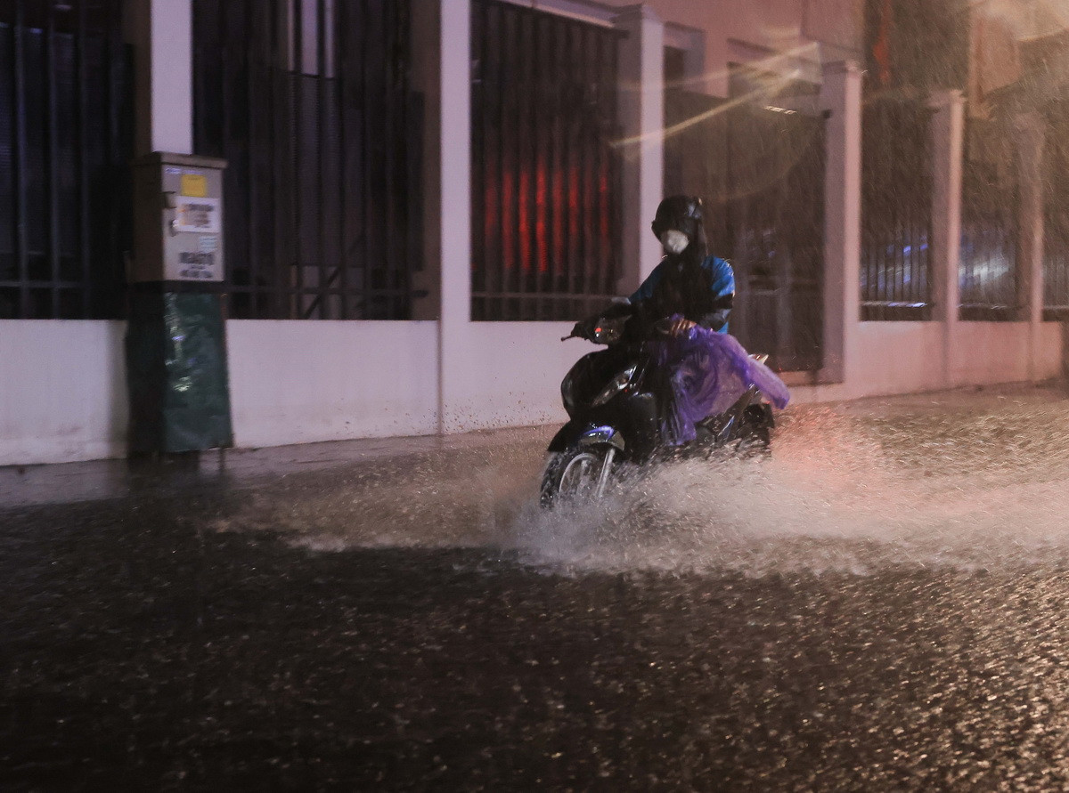 Người dân di chuyển khó khăn qua đoạn ngập trên phố Trần Quốc Toản, quận Hoàn Kiếm. (Ảnh: Hoàng Hiếu/TTXVN)