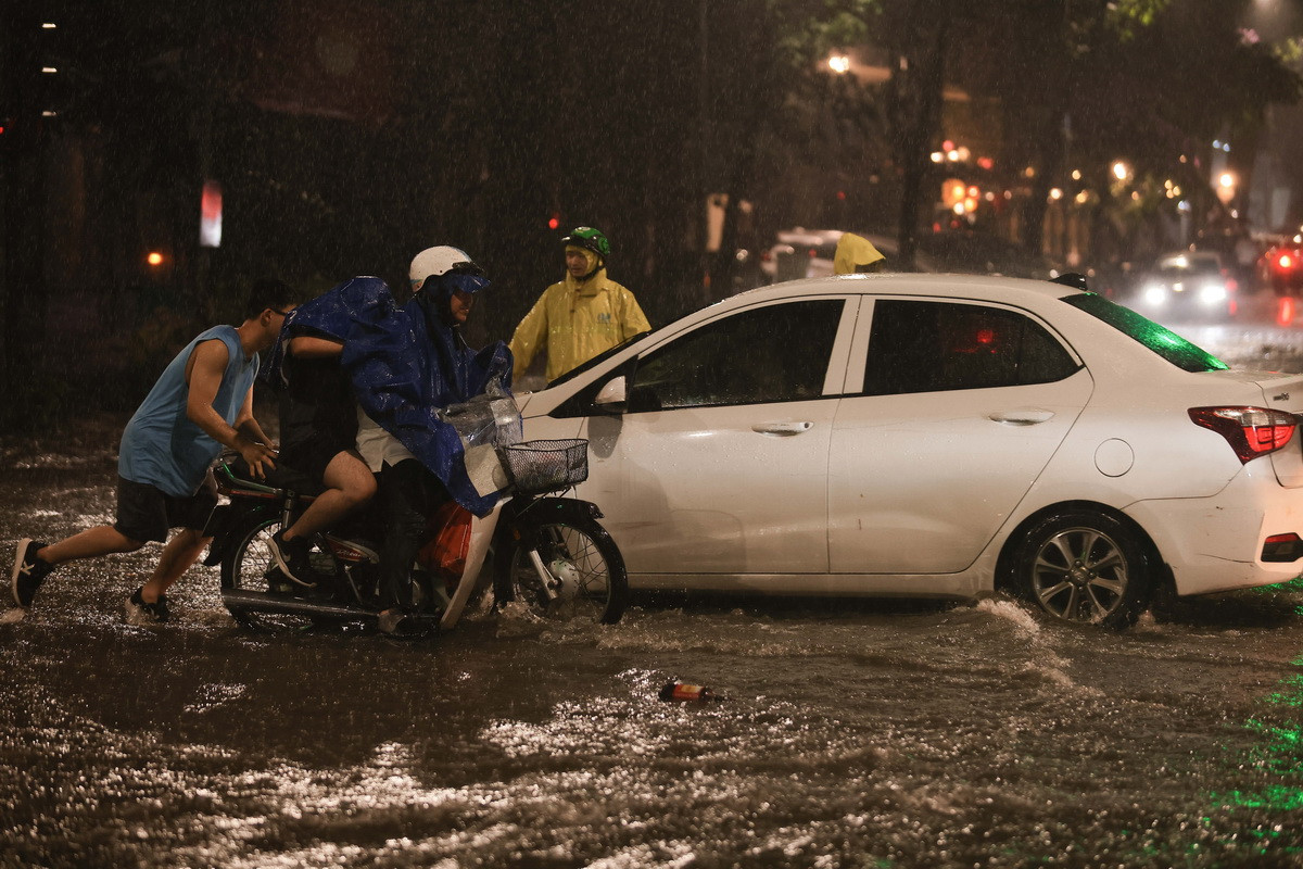 Một chiếc xe chết máy khi đi qua đoạn ngập phố Lý Thường Kiệt. (Ảnh: Hoàng Hiếu/TTXVN)