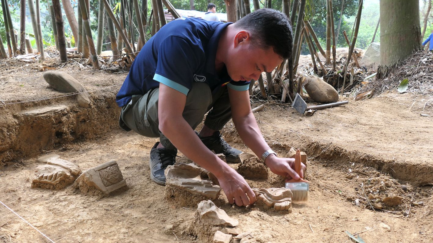 Ông Nguyễn Đức Bình, Viện Khảo cổ học, đang xử lý di vật xuất lộ trong hố khai quật.