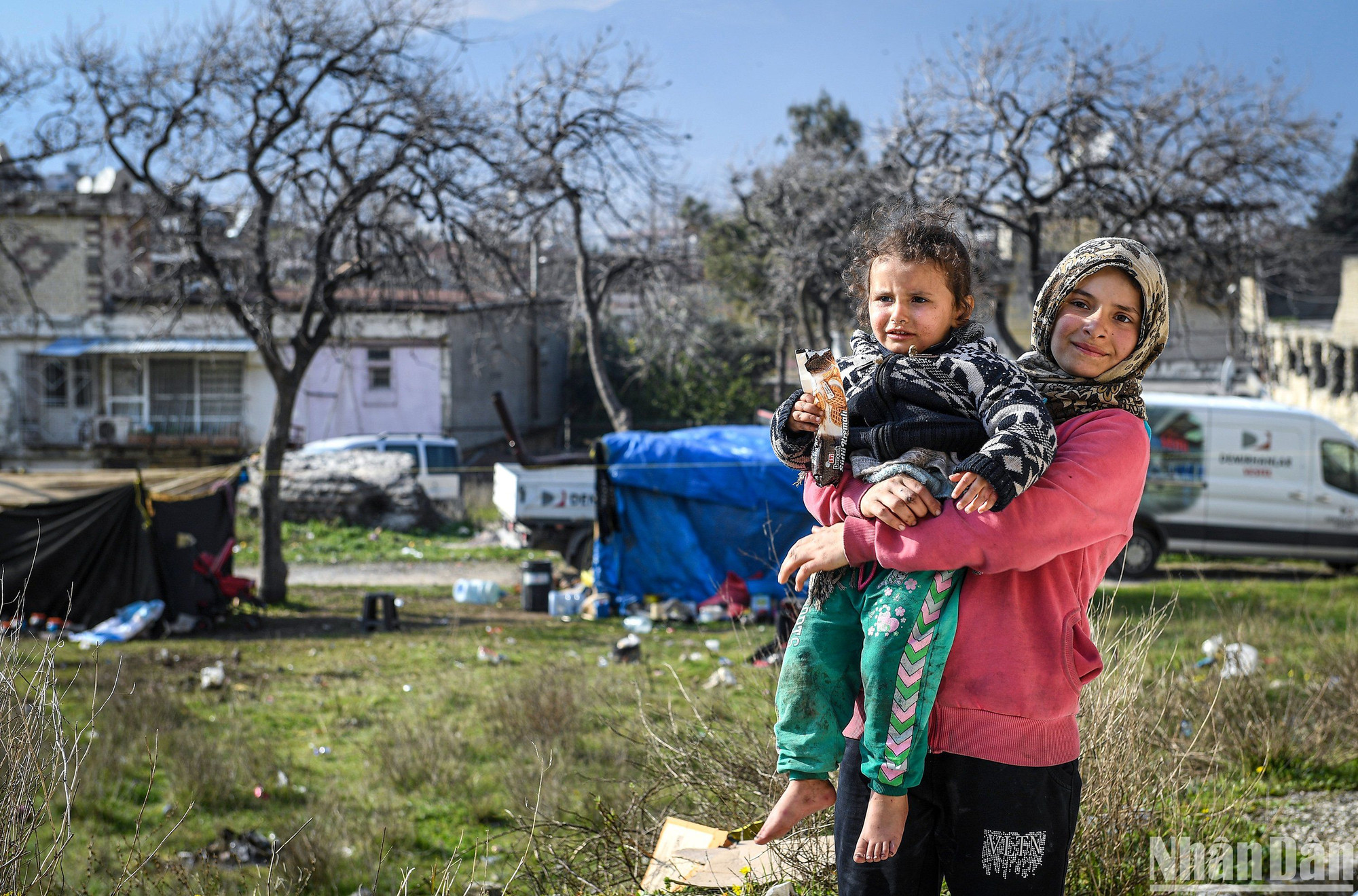 Trẻ em, thay vì đến trường để học, lại phải học cách giúp người lớn mưu sinh. Các em đi nhặt củi, nhóm than hoặc trở thành bảo mẫu khi cha mẹ vắng nhà. Trong ảnh, Eyhem (bên phải) đang trông coi em gái. Phía sau là chiếc lều kỷ lục khi có tới 28 người cùng sinh hoạt. (Ảnh: Thành Đạt)