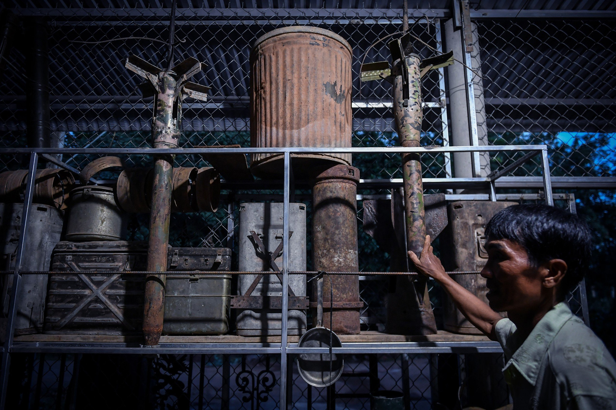 Phan Tấn Hoàng bên những "di vật" thời chiến. Trong ảnh, nhân vật với "Cây nhiệt đới" - một phần trong hàng rào điện tử McNamara trứ danh từng bao vây chung quanh xã Hải Thái trong thời chiến. (Ảnh: Thành Đạt)