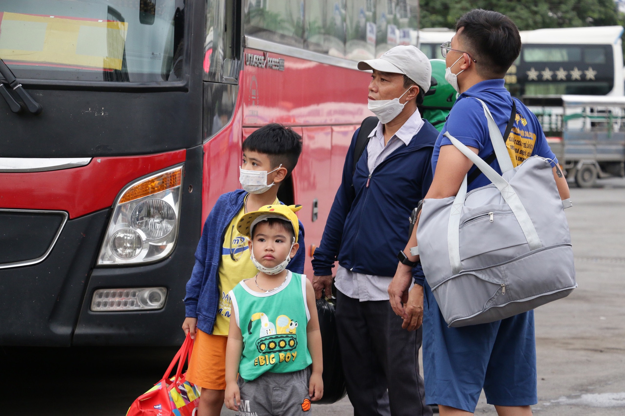 Những em nhỏ cùng gia đình đứng đợi để lên chuyến xe về quê nghỉ lễ.