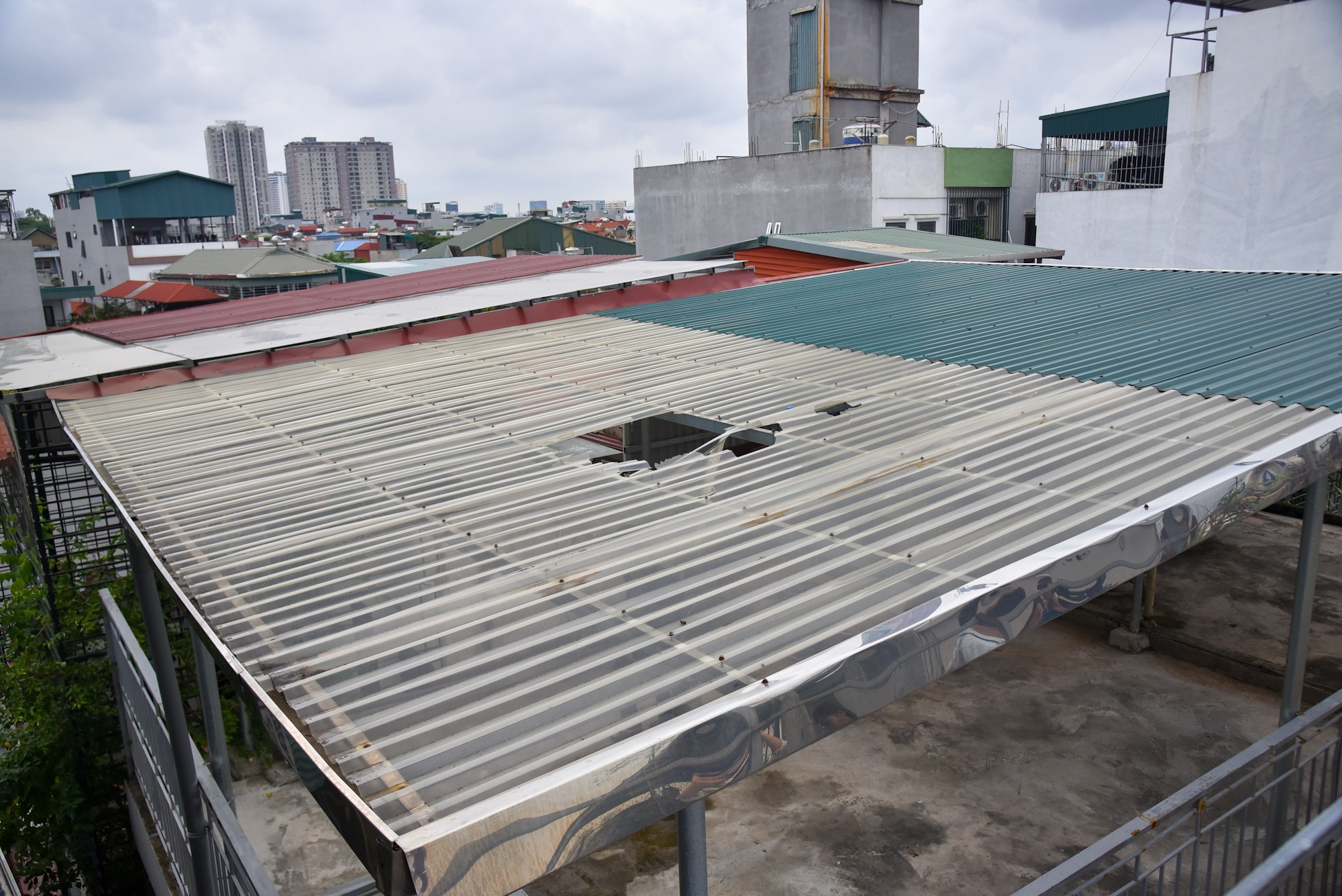 Tầng mái tôn một căn nhà kế bên chung cư bị cháy. Vết thủng trên mái là hậu quả của việc người dân nhảy xuống để thoát nạn.