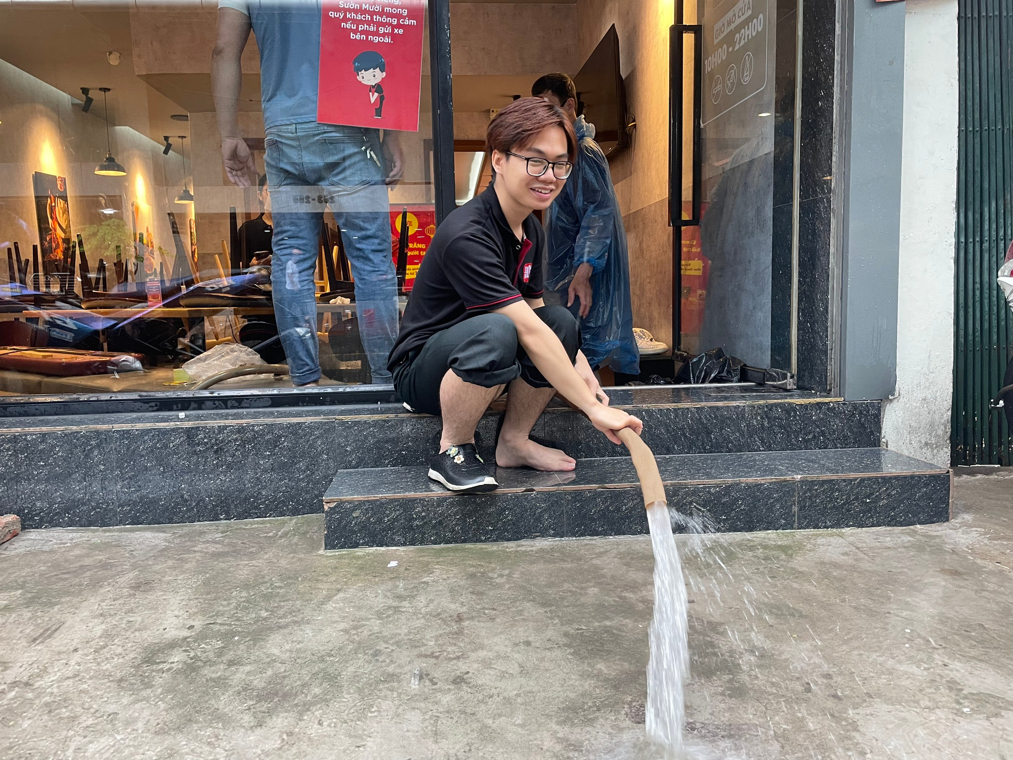 Nhân viên một quán cafe bơm nước ra bên ngoài.