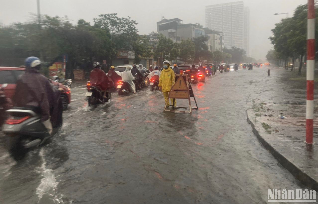 Tại quận Nam Từ Liêm, các phương tiện di chuyển khó khăn khi nước đã ngập hết phần lòng đường. Công nhân thoát nước phải có mặt để thực hiện các phương án thoát nước theo quy định.
