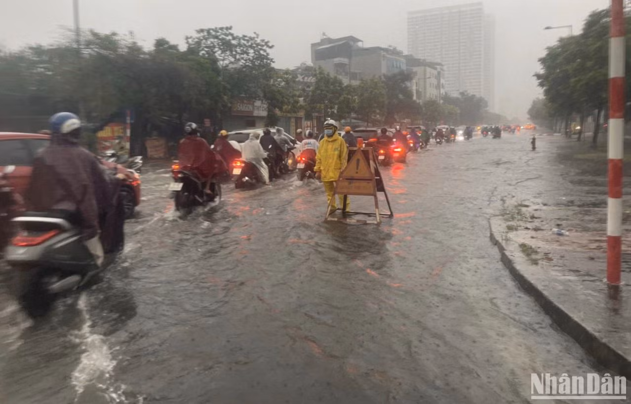 Tại quận Nam Từ Liêm, các phương tiện di chuyển khó khăn khi nước đã ngập hết phần lòng đường. Công nhân thoát nước phải có mặt để thực hiện các phương án thoát nước theo quy định.