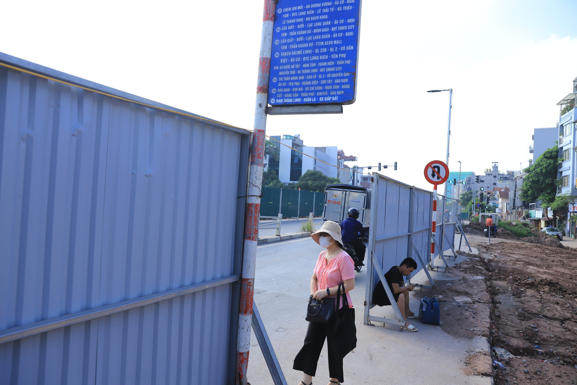 Điểm chờ xe buýt của người dân nằm ẩn sâu sau các tấm tôn ngăn tạm. Để tới được điểm đón xe này, các hành khách bắt buộc phải đi xuống lòng đường cùng... xe cộ khác.