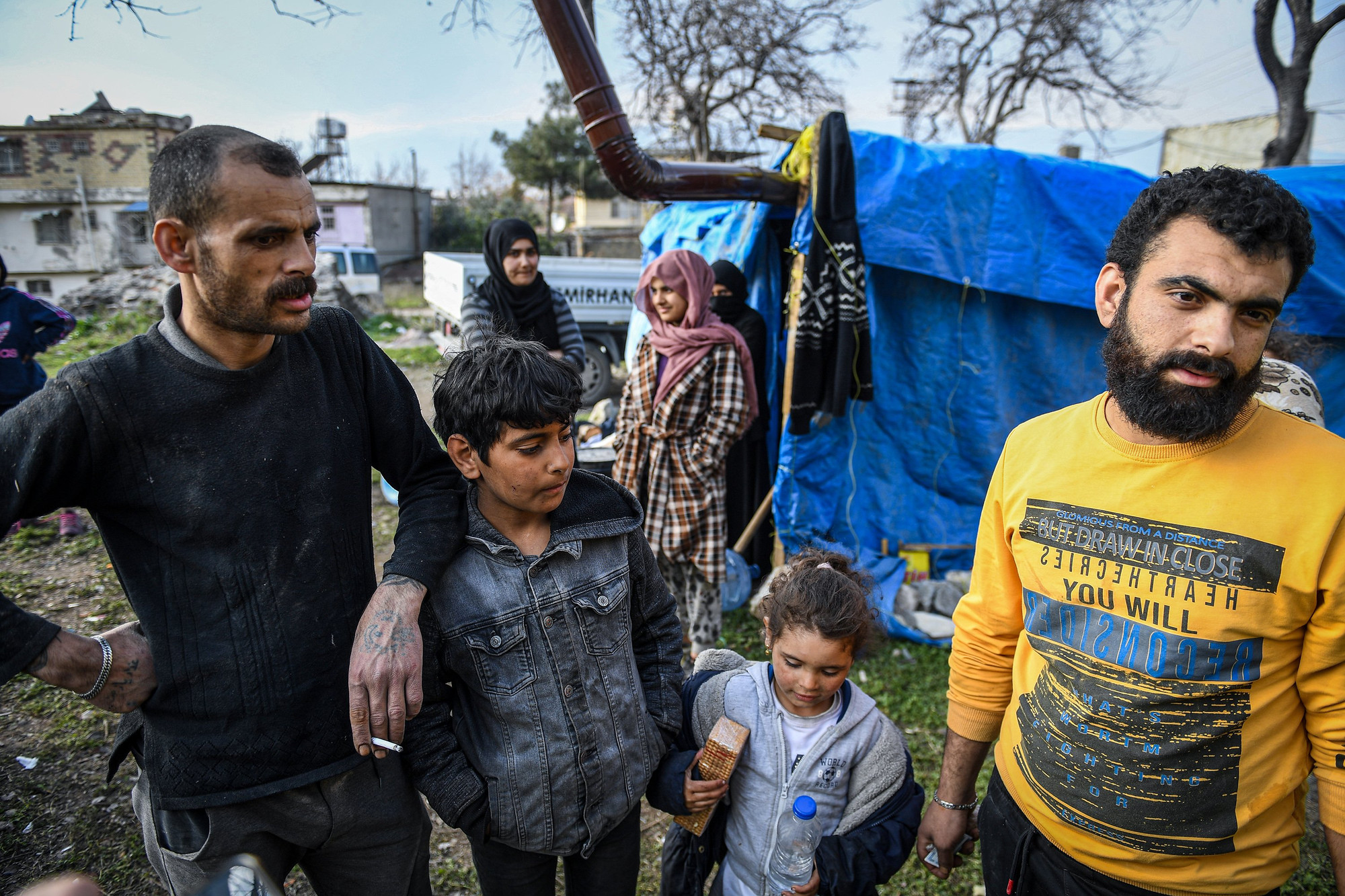 Ahmet (ngoài cùng bên trái) đã nhặt lại những đồ dùng được sau địa chấn để dựng nên chiếc lều tạm. Phía bên ngoài, gạch, đá được chèn để chống gió thổi bay. (Ảnh: Thành Đạt)