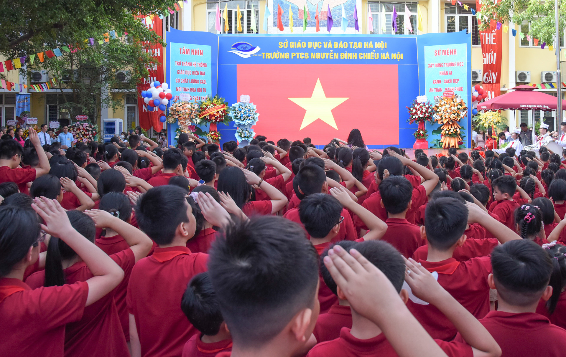 Các đại biểu cùng các thầy cô giáo, các em học sinh thực hiện nghi thức chào cờ tại buổi lễ.