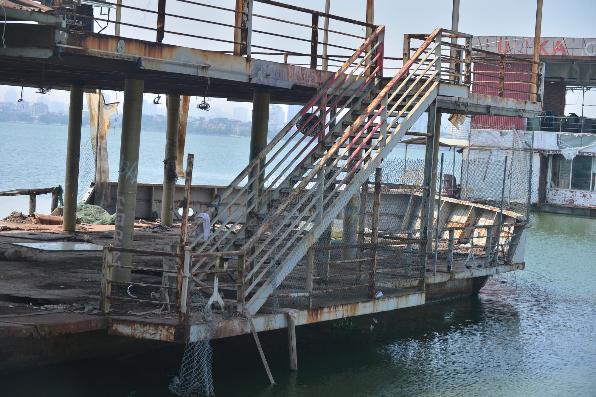 Hàng rào vắt xuống mặt hồ. Bên trên mặt ngổn ngang rác và la liệt những hình vẽ bằng sơn...