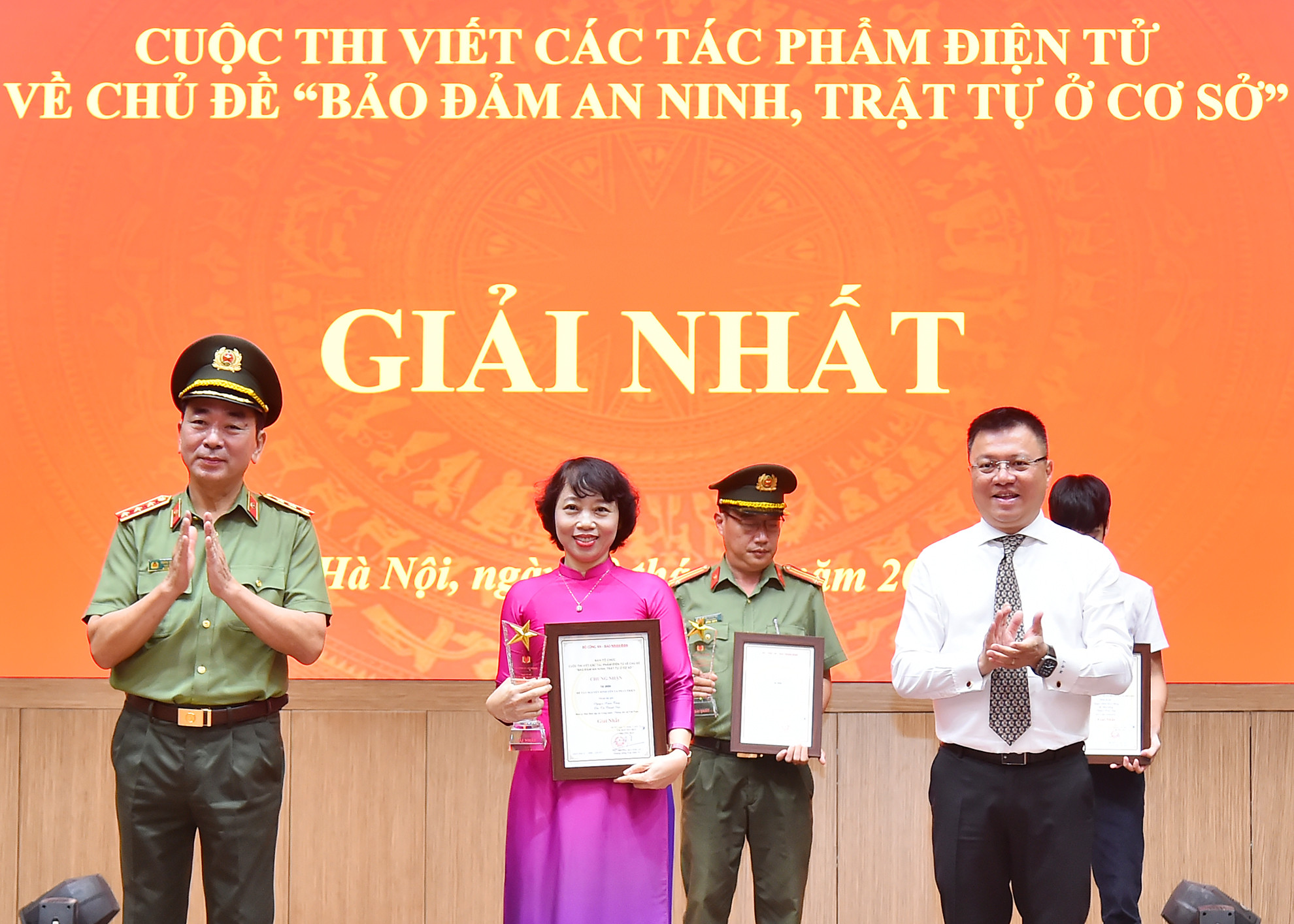Các đồng chí Ủy viên Trung ương Đảng: Thượng tướng Trần Quốc Tỏ, Phó Bí thư Đảng ủy Công an Trung ương, Thứ trưởng điều hành hoạt động của Bộ Công an, Trưởng Ban Tổ chức cuộc thi; Lê Quốc Minh, Tổng Biên tập Báo Nhân Dân, Phó Trưởng Ban Tuyên giáo Trung ương, Chủ tịch Hội Nhà báo Việt Nam trao giải Nhất cho tác giả tại lễ tổng kết. (Ảnh: THỦY NGUYÊN)