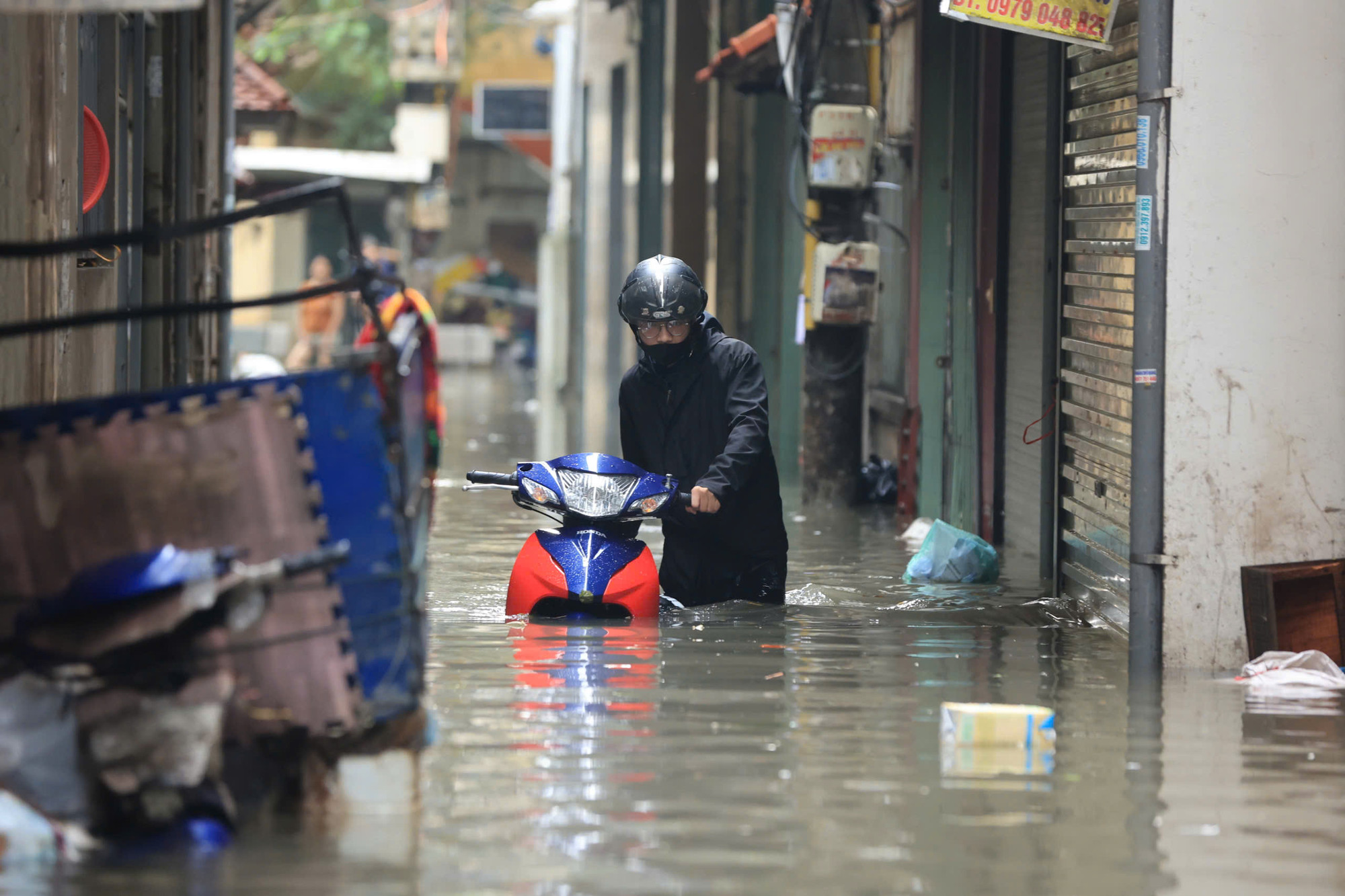 Một nam thanh niên với chiếc xe máy đã gần như chìm nghỉm trong nước.