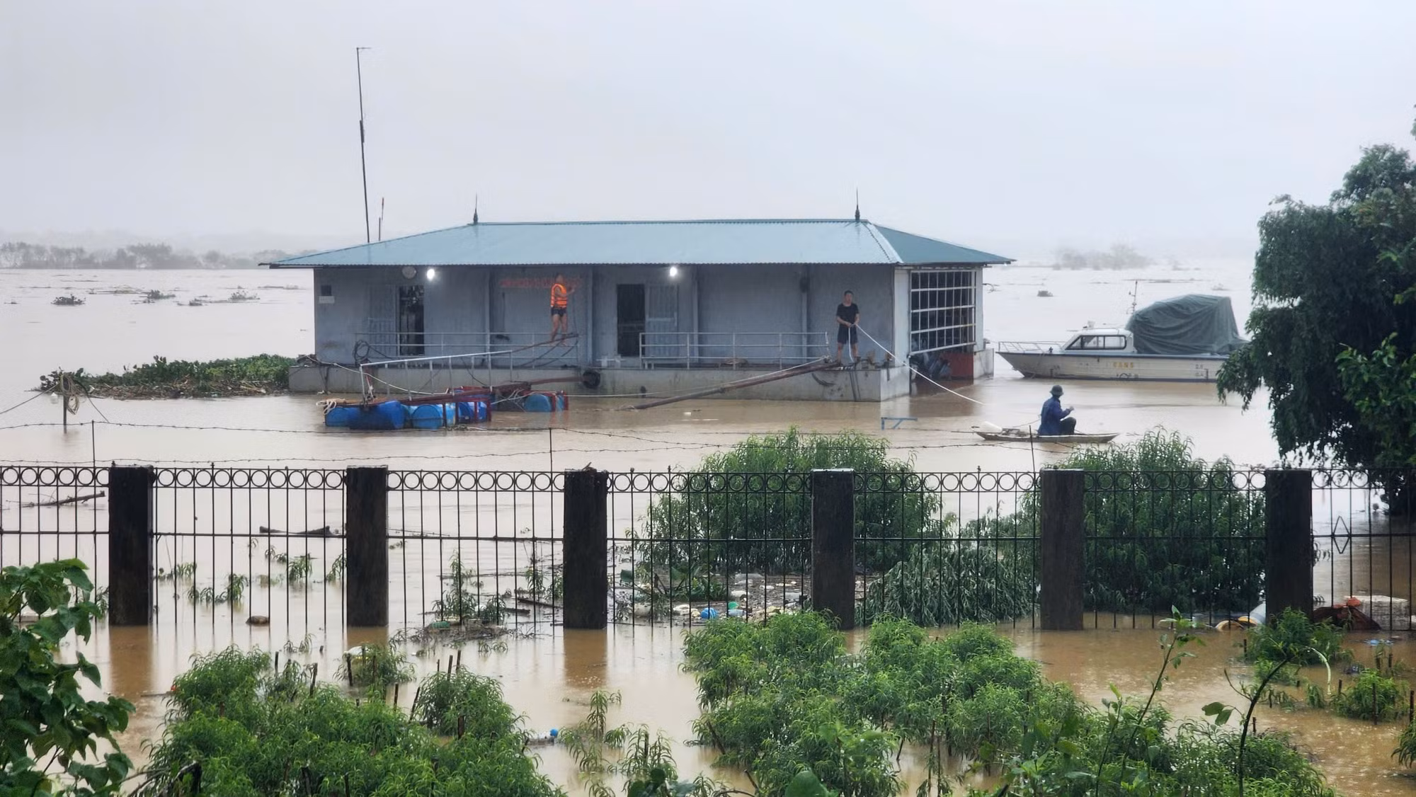 Nước dâng cao ngập một nửa hàng rào bao quanh một công trình bên phía ngoài đê An Dương Vương.