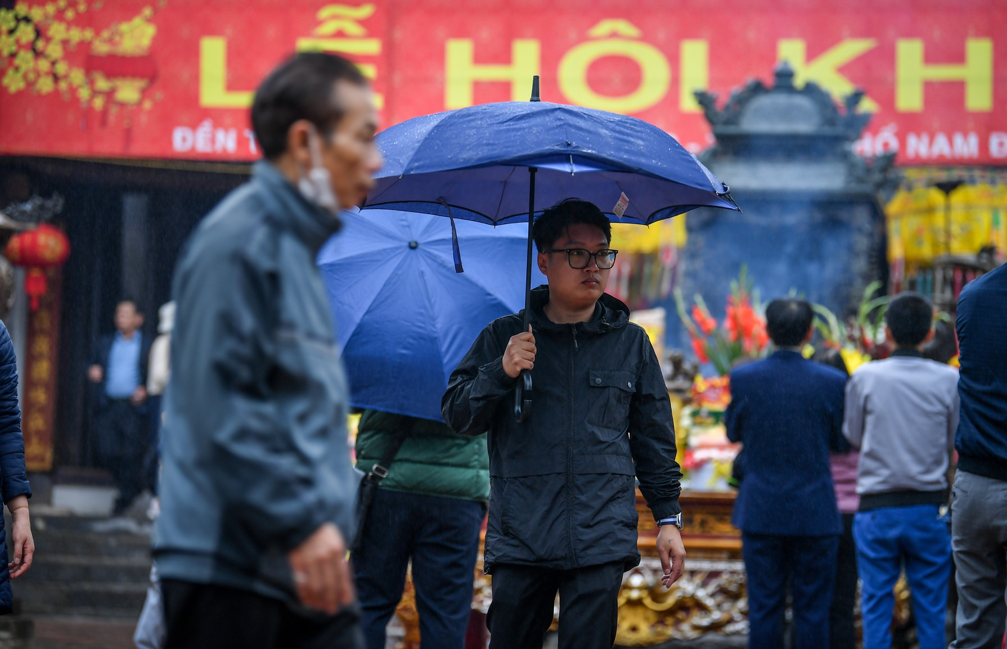 Chiều 23/2, mặc dù mưa lớn, nhiều du khách vẫn đội mưa dâng hương tại đền Trần.