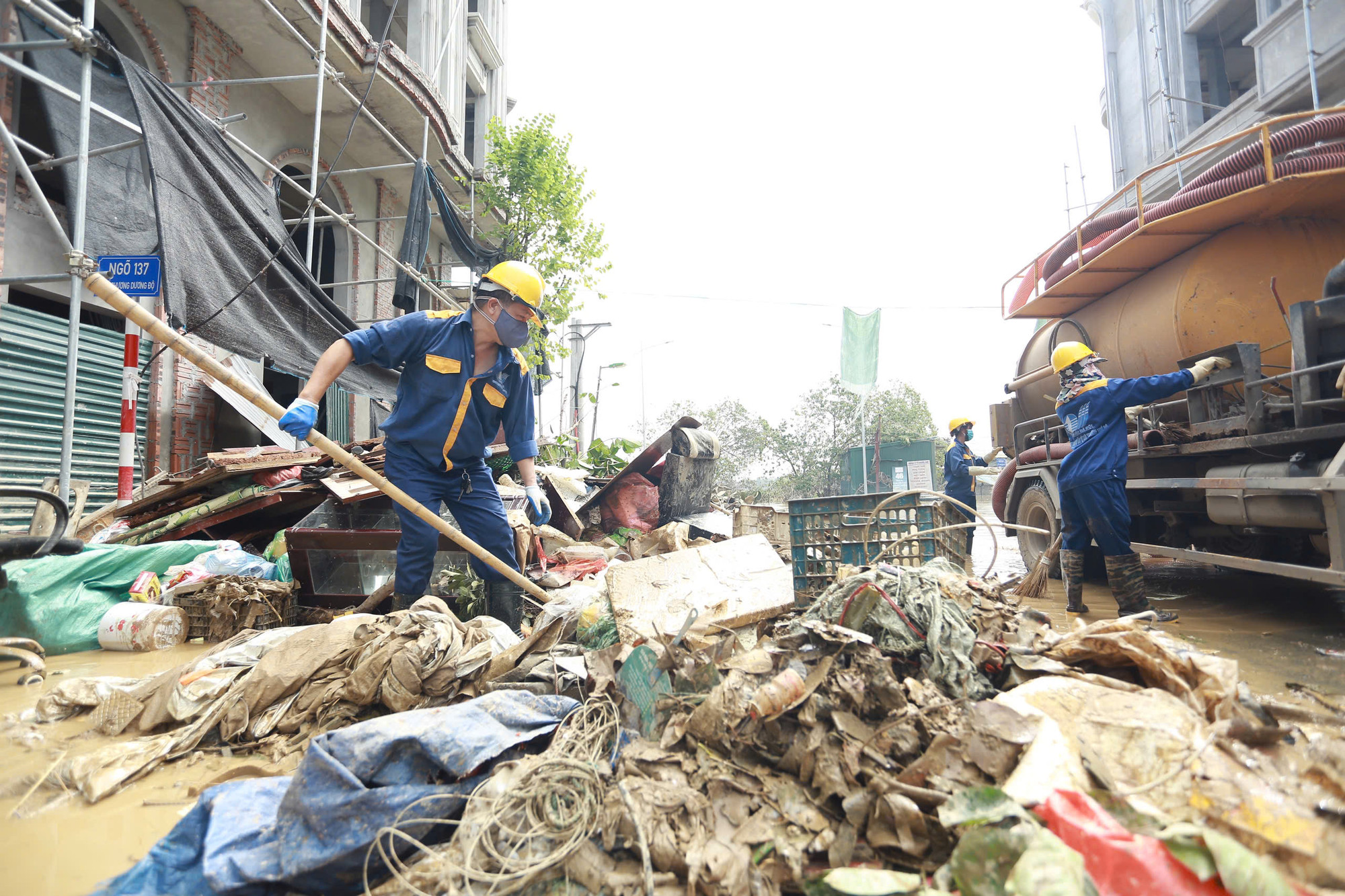 Công nhân Công ty TNHH MTV Thoát nước Hà Nội hỗ trợ người dân dọn rác thải sau đợt lụt.