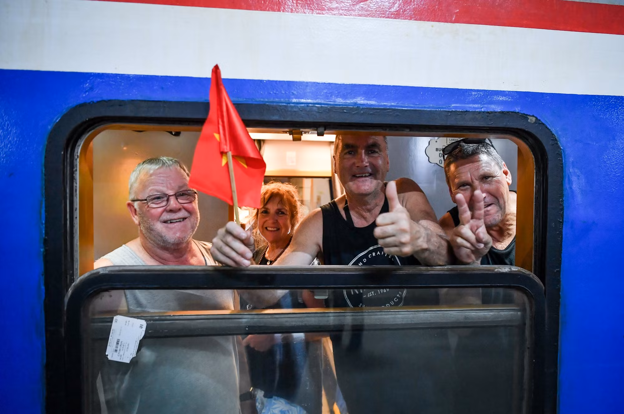 Những du khách nước ngoài thích thú với đoàn tàu lan tỏa màu Quốc kỳ Việt Nam.