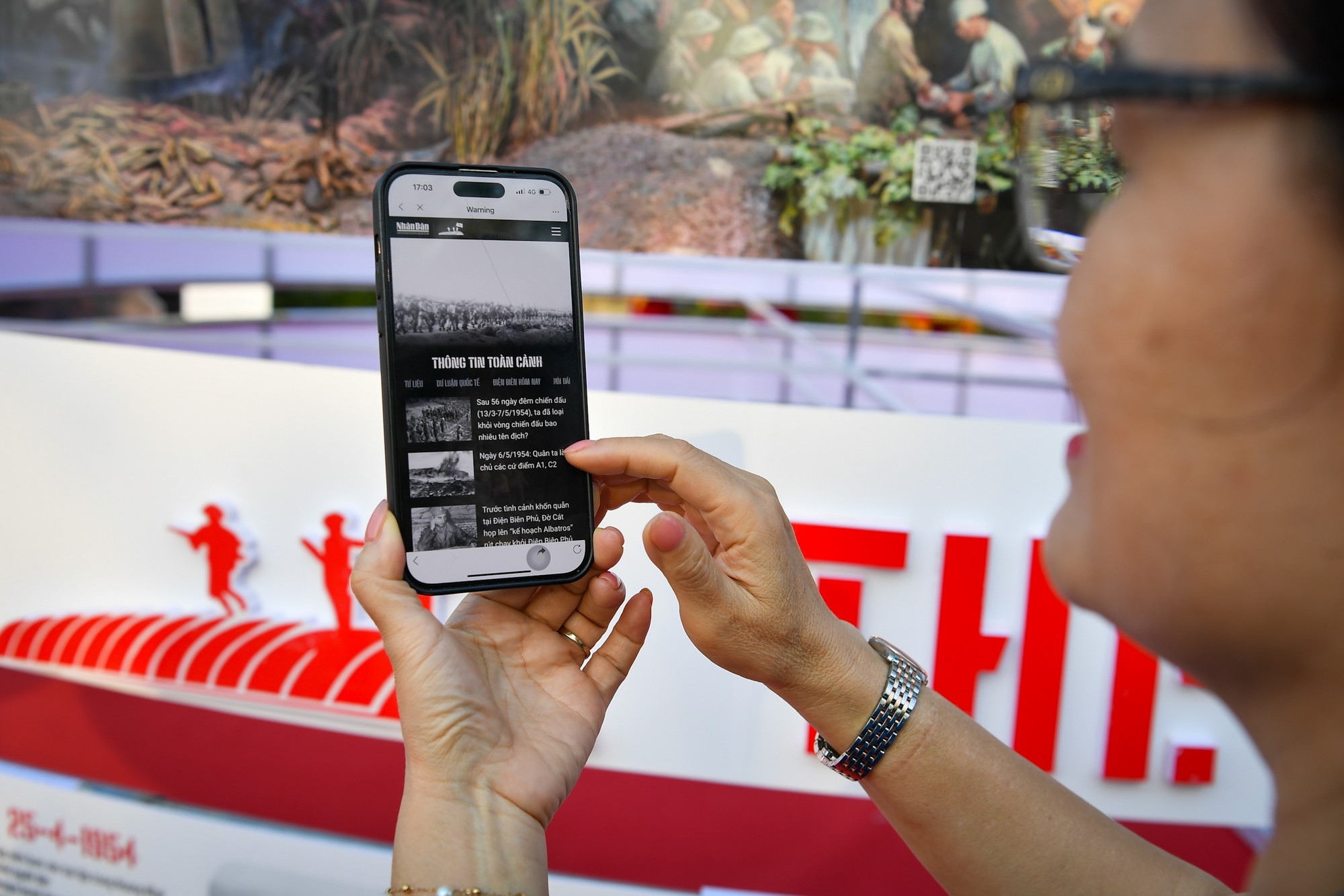 Một du khách thích thú với chuyên trang đặc biệt Chiến thắng Điện Biên Phủ của Báo Nhân Dân.