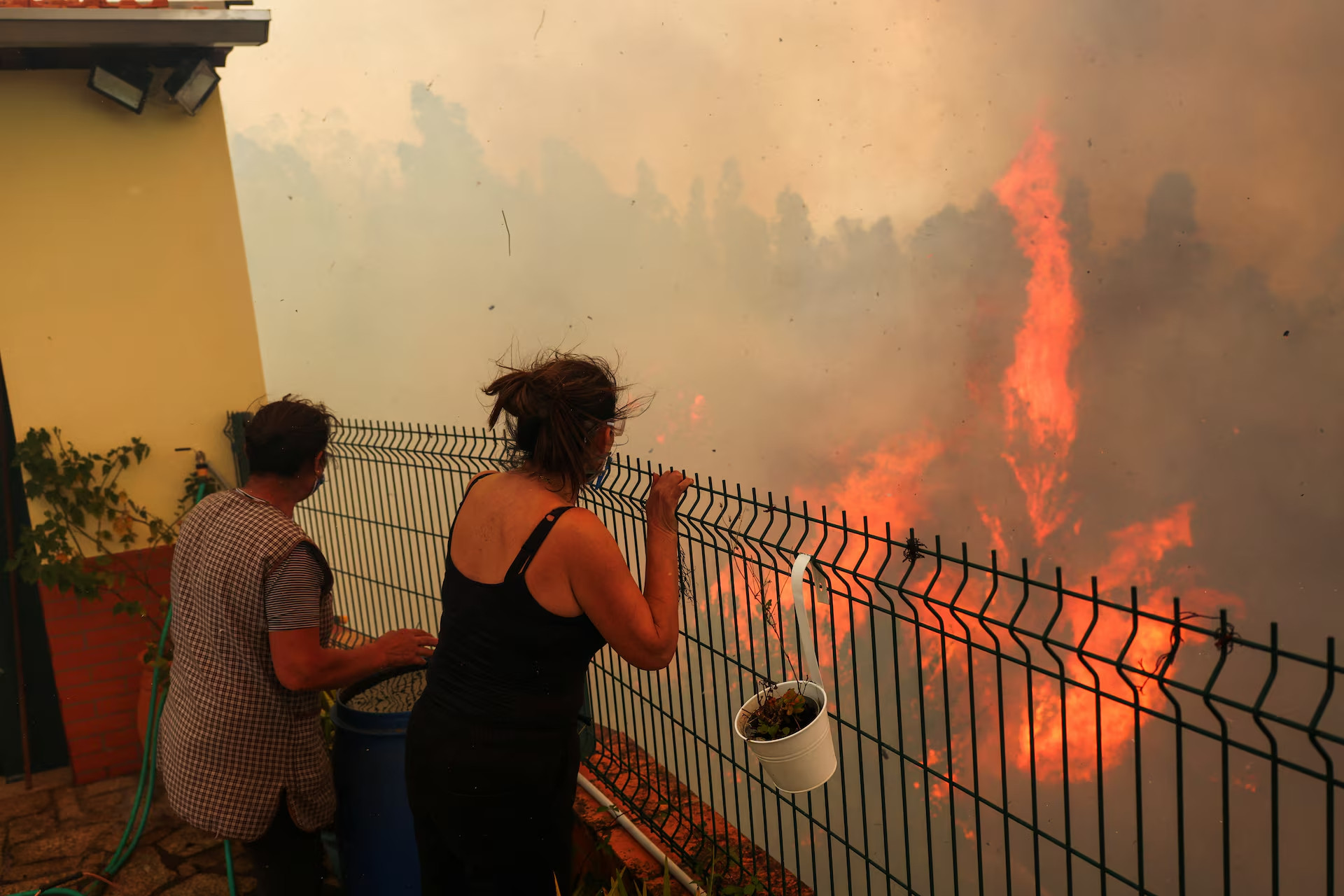 Hai người phụ nữ theo dõi đám cháy rừng bên cạnh ngôi nhà của họ ở Vilarinho, Bồ Đào Nha.