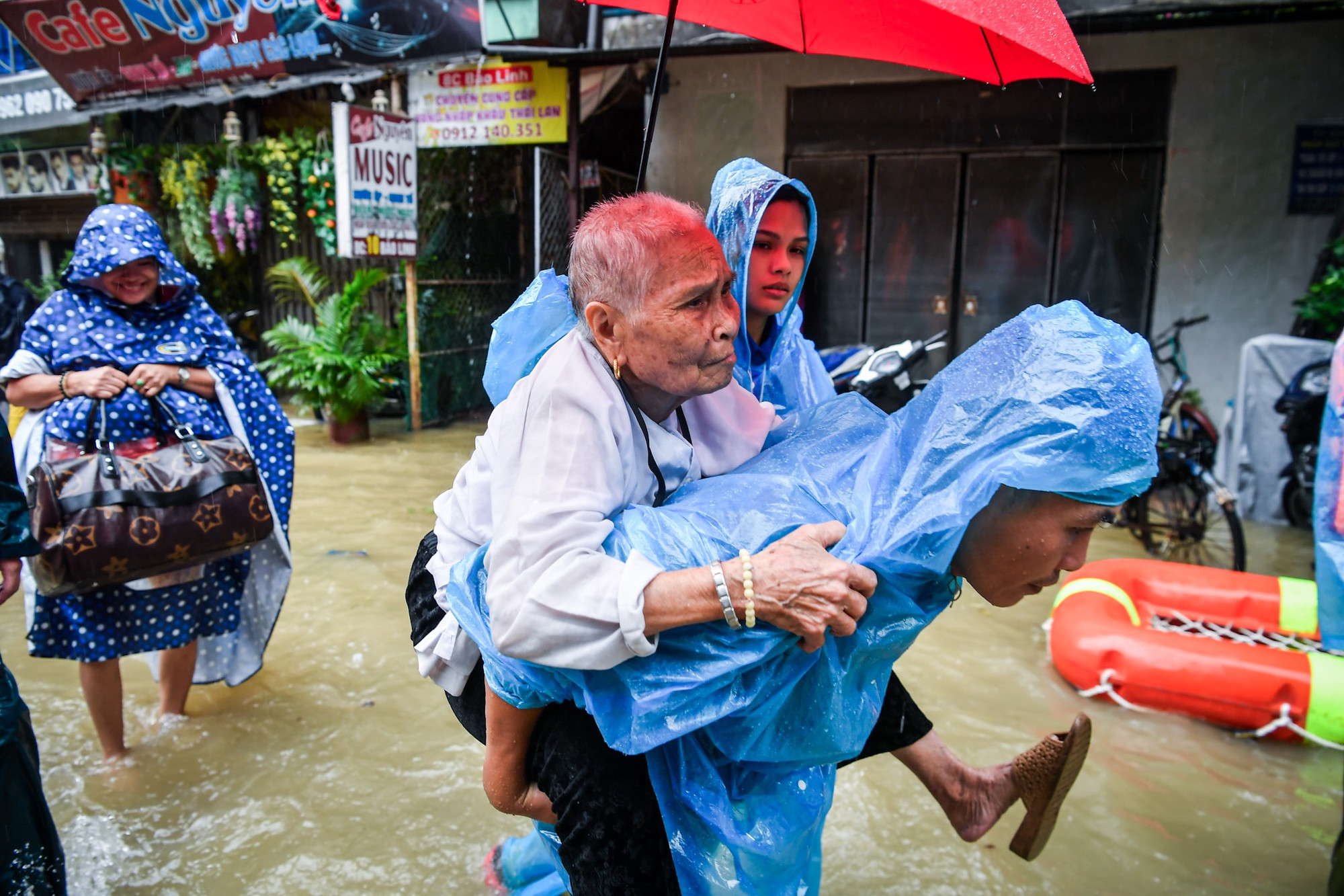 Cõng một cụ bà cao tuổi rời khỏi vùng ngập sâu.