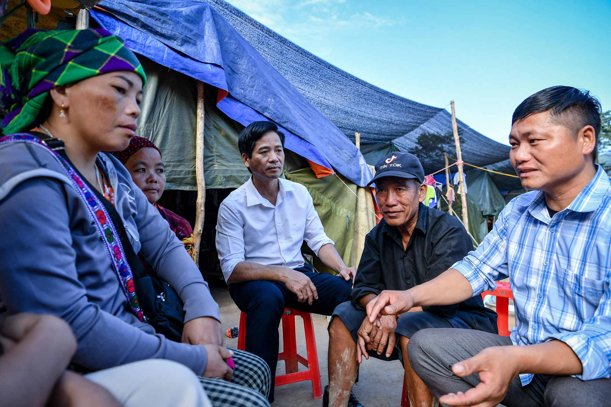 Bí thư Chi bộ thôn Nậm Tông Lù Seo Nương (bìa phải) trò chuyện cùng bà con tại điểm tạm cư.