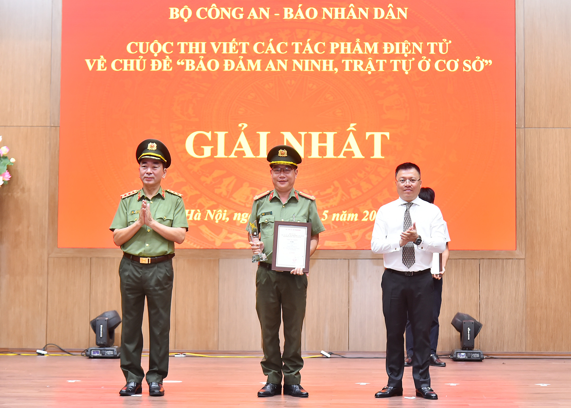 Các đồng chí Ủy viên Trung ương Đảng: Thượng tướng Trần Quốc Tỏ, Phó Bí thư Đảng ủy Công an Trung ương, Thứ trưởng điều hành hoạt động của Bộ Công an, Trưởng Ban Tổ chức cuộc thi; Lê Quốc Minh, Tổng Biên tập Báo Nhân Dân, Phó Trưởng Ban Tuyên giáo Trung ương, Chủ tịch Hội Nhà báo Việt Nam trao giải Nhất cho tác giả tại lễ tổng kết. (Ảnh: THỦY NGUYÊN)