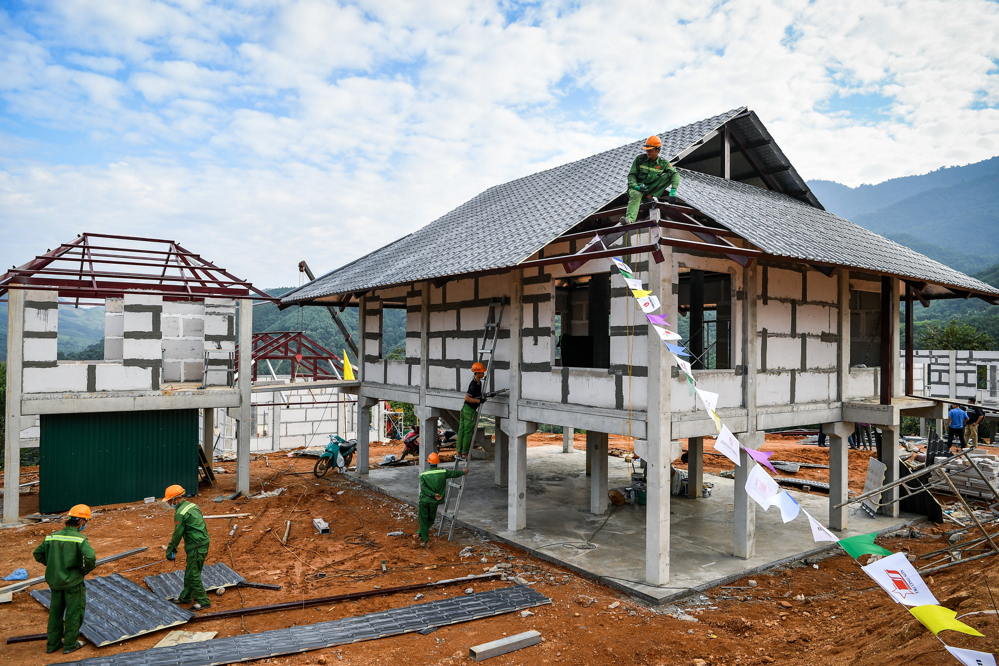 Để rút ngắn thời gian, đơn vị thi công đã đúc sẵn cột và dầm đỡ bằng bê-tông và các tấm panen lát sàn từ một địa điểm rồi vận chuyển đến công trường để lắp đặt thành khung nhà sàn hoàn chỉnh. Hiện tại, những ngôi nhà sàn đầu tiên bao gồm lắp tường và lợp mái, cùng với bếp đã được hoàn thiện.