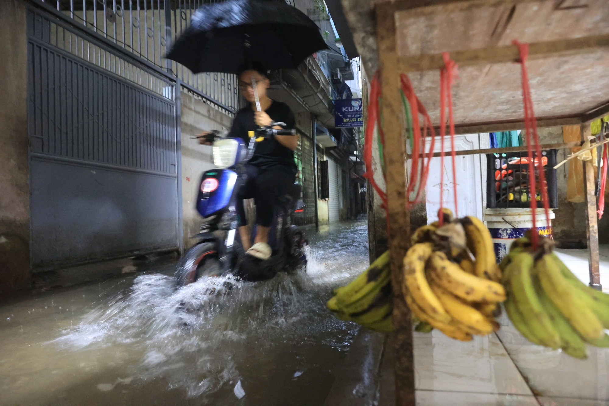 Tới sáng sớm 23/8, mặc dù mưa đã giảm, nhưng nhiều tuyến phố vẫn bị ngập. Trong ảnh, một người dân cố gắng di chuyển qua con ngõ ngập nước tại Tân Triều.