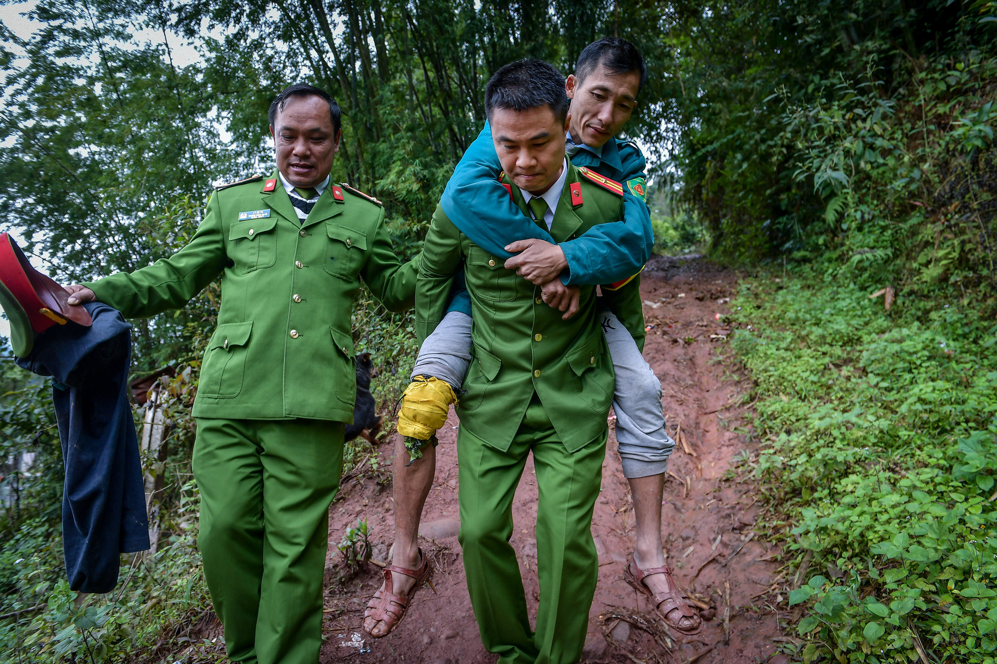Trung tá Lý Xú Tư và Thiếu tá Bùi Quang Khải cõng một người dân bị thương ở chân khi đi rừng xuống con dốc xuống bản Tả Kố Khừ.