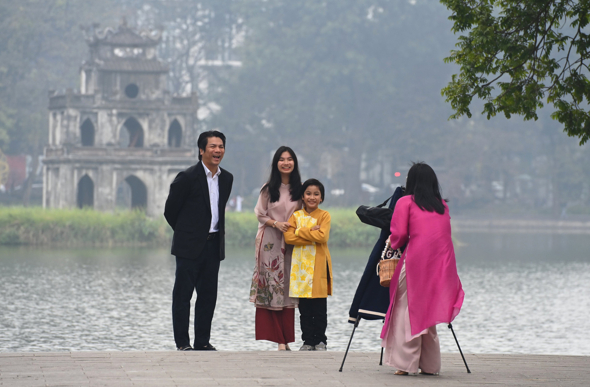 Một gia đình chụp hình lưu niệm trước Tháp Rùa, biểu tượng của hồ Gươm trong sáng mùng Một mờ sương thật đẹp. (Ảnh: THÀNH ĐẠT)
