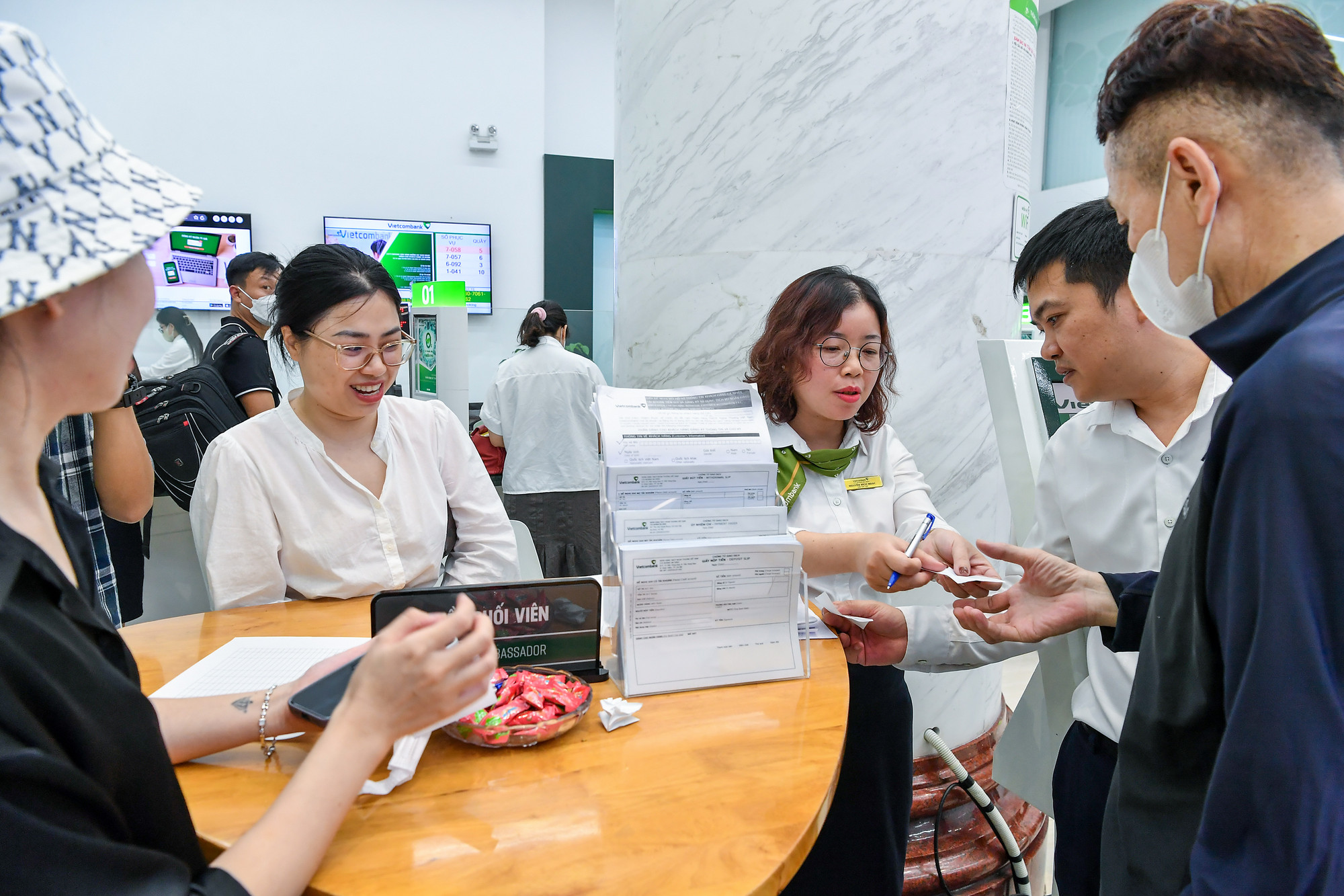 Nhân viên ngân hàng Vietcombank điều phối lấy số thứ tự cho khách mua vàng.