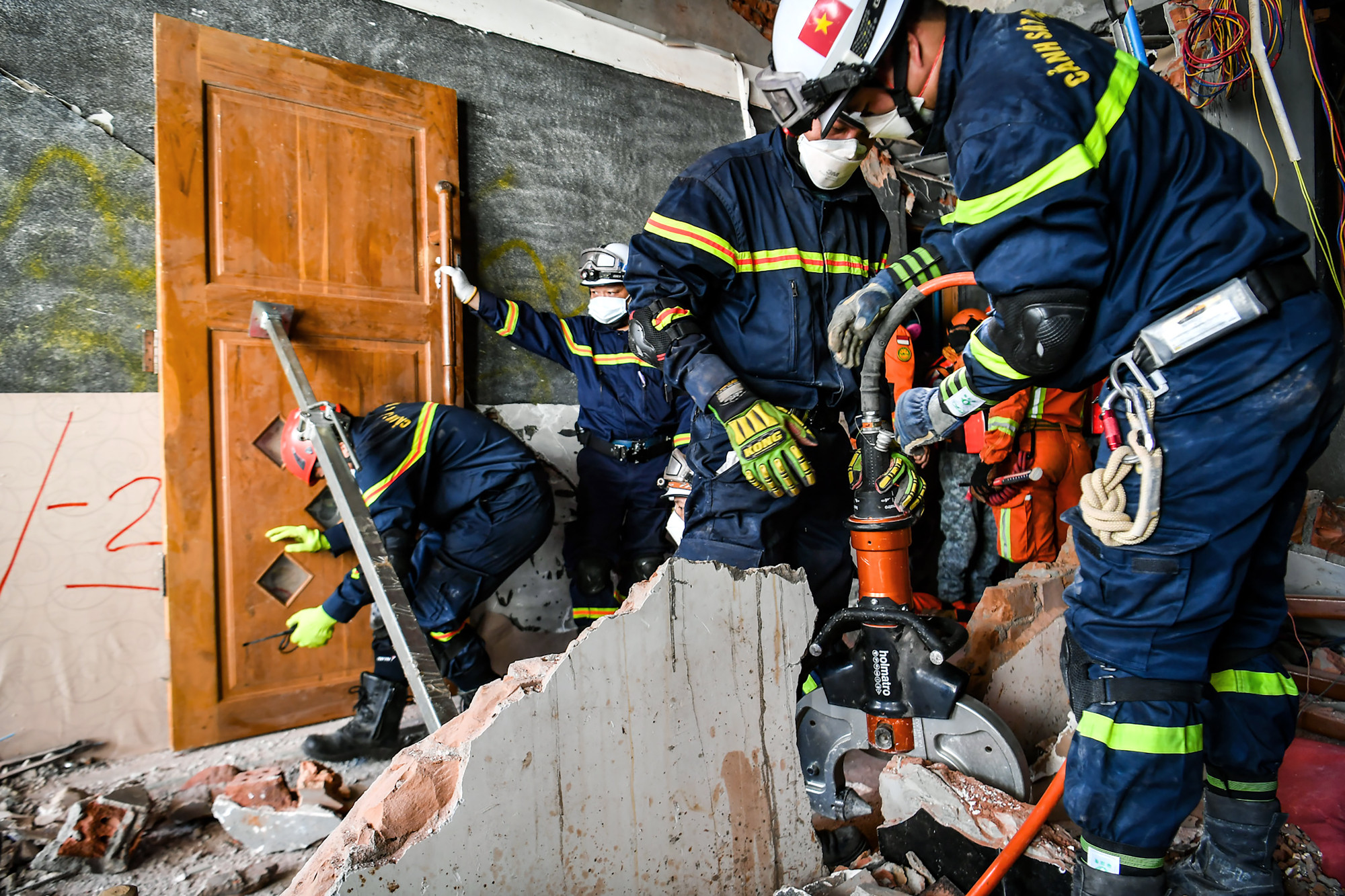 Lực lượng cứu hộ Việt Nam dùng kìm thủy lực phá bê-tông cùng hệ thống thanh chịu lực để bảo đảm không làm rung chấn kết cấu các tòa nhà.