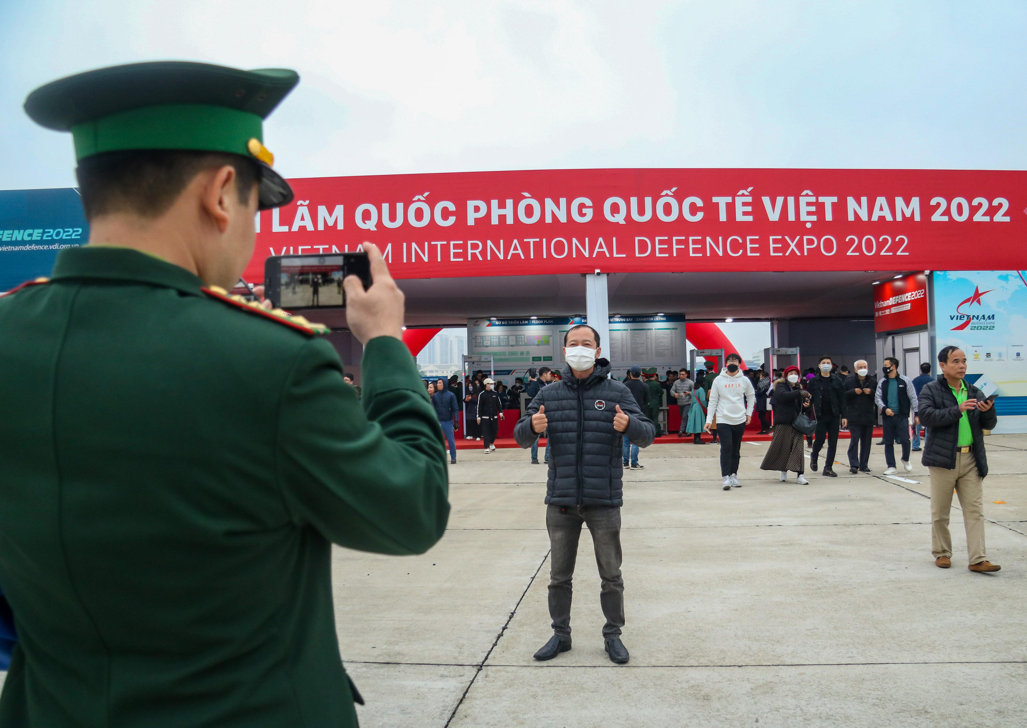 Một quân nhân vui vẻ chụp hình kỷ niệm cho người dân tại cổng chào của buổi triển lãm.