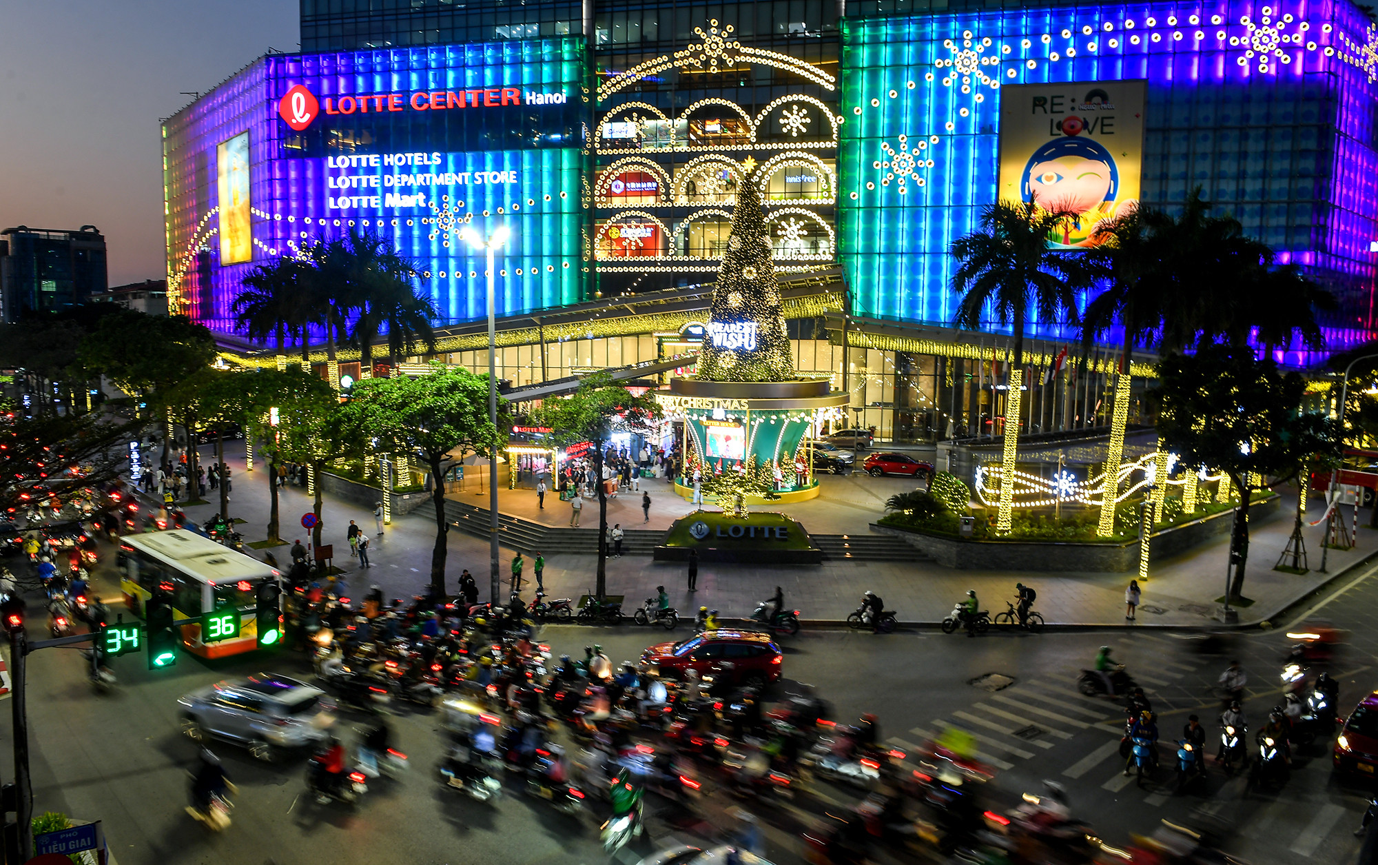 Khu vực sảnh lớn trước cửa trung tâm thương mại Lotte nằm trên phố Đào Tấn (quận Ba Đình), cây thông lớn cao hơn 20m đã được dựng lên, trang hoàng lộng lẫy làm nổi bật một góc phố.