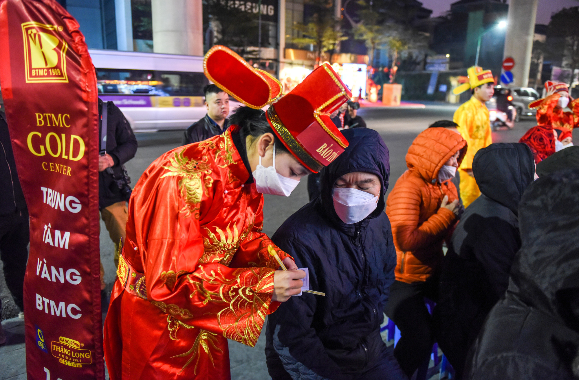 Càng tới gần thời điểm 6 giờ 30 phút, lượng khách tới càng đông. Các nhân viên trong trang phục Thần Tài hướng dẫn khách hàng đăng ký số để chuẩn bị mua vàng cầu may dịp đầu năm.