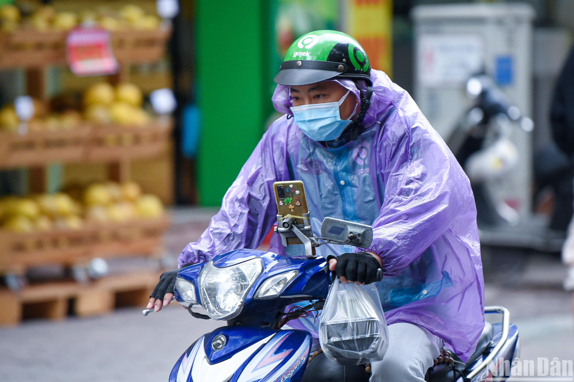 Những người làm thường làm công việc di chuyển ngoài đường phải mặc thêm áo mưa để tránh gió lạnh. (Ảnh: THÀNH ĐẠT)