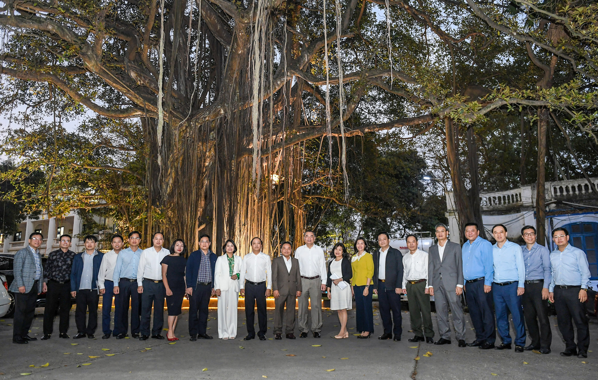 Các đại biểu của hai đơn vị chụp ảnh lưu niệm dưới cây đa truyền thống trong khuôn viên Báo Nhân Dân.