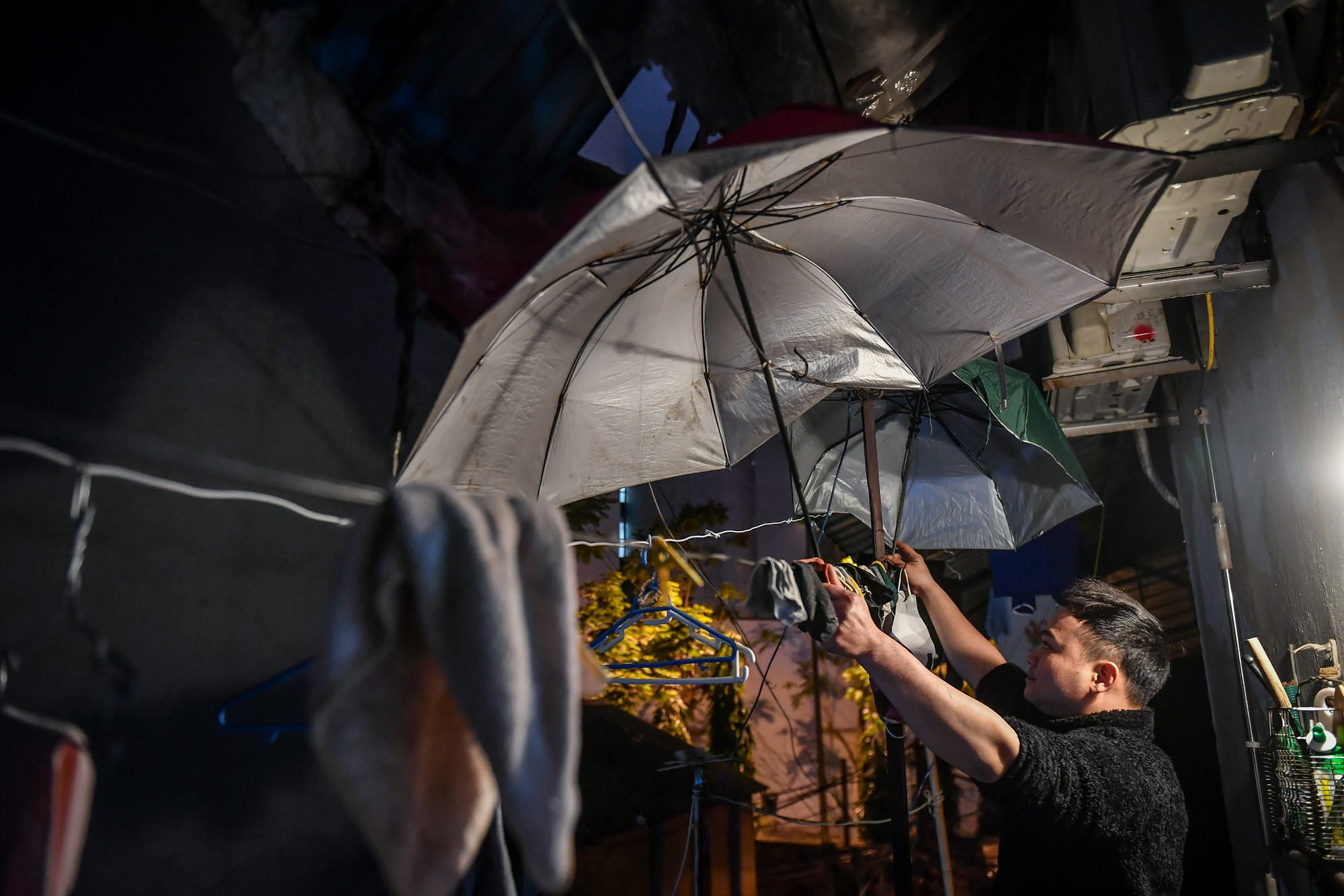 Băng, một cư dân lâu năm xóm chạy thận dùng 2 chiếc ô cũ che chắn lại trước hiên nhà để hạn chế gió lùa. Đó cũng là những cách "đơn sơ" nhất mà cư dân trong xóm nghĩ ra để chống rét. Ảnh: THÀNH ĐẠT Băng, một cư dân lâu năm xóm chạy thận dùng 2 chiếc ô cũ che chắn lại trước hiên nhà để hạn chế gió lùa. Đó cũng là những cách "đơn sơ" nhất mà cư dân trong xóm nghĩ ra để chống rét. Ảnh: THÀNH ĐẠT