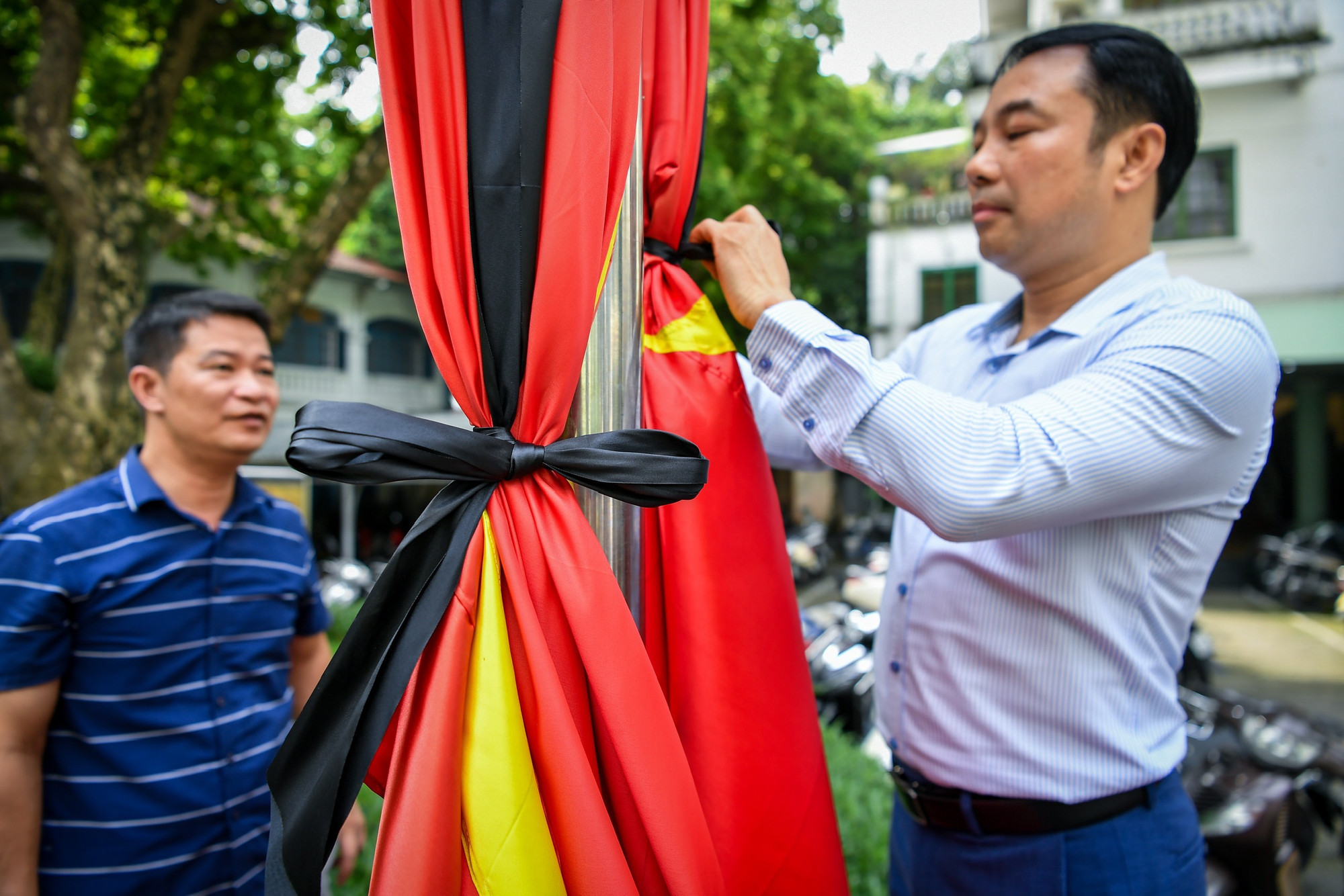 Cán bộ, nhân viên Báo Nhân Dân cẩn thận, trang nghiêm thực hiện treo cờ rủ.