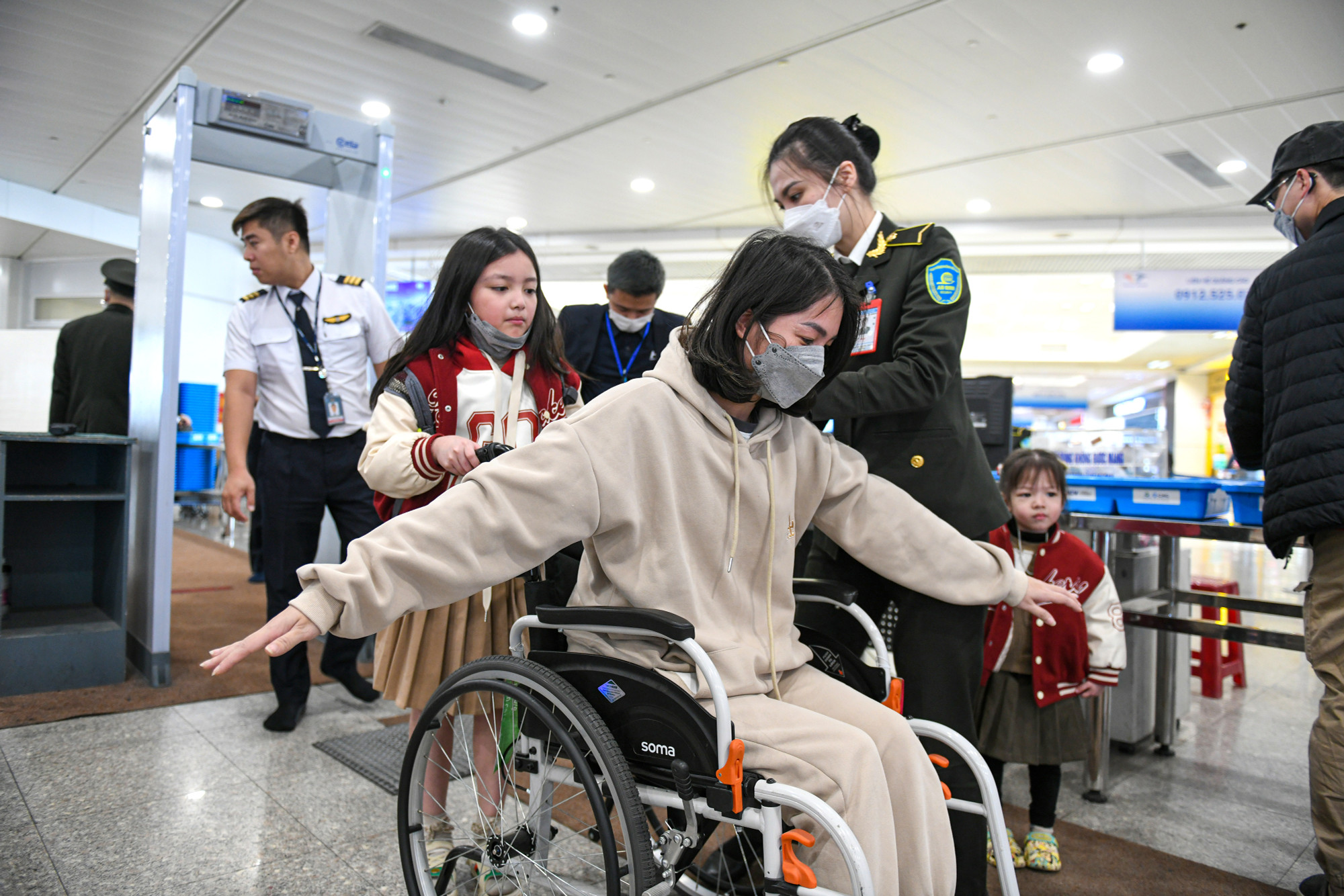 Một hành khách phải ngồi xa lăn lên máy bay được nhân viên an ninh ân cần kiểm tra theo các bước.