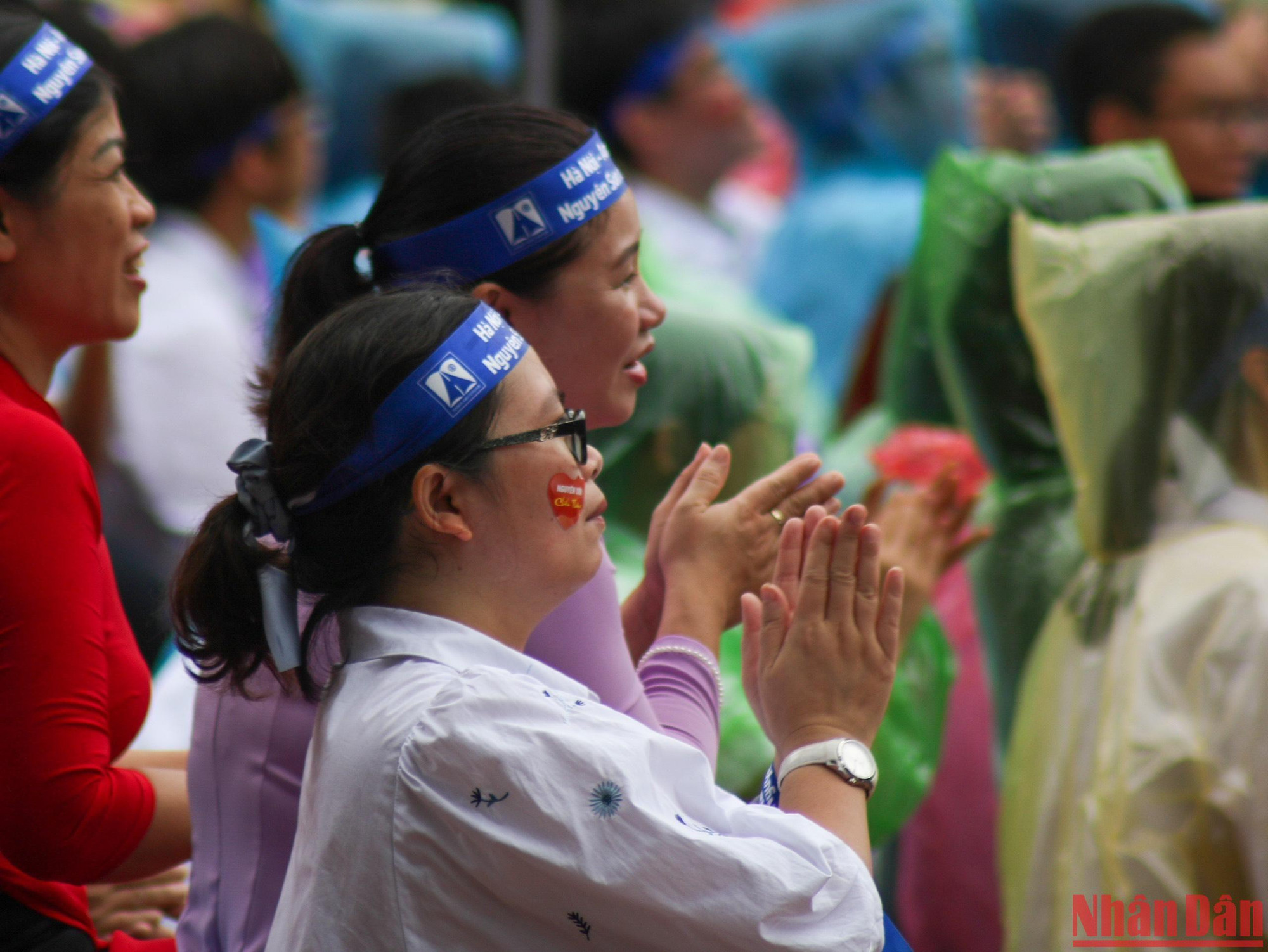 Sáng nay, thời tiết Hà Nội có mưa nhỏ từng đợt nhưng các cô giáo cùng học sinh Trường THPT chuyên Hà Nội-Amsterdam "đội mưa" cổ vũ cho các thí sinh. (Ảnh: Nhật Quang)