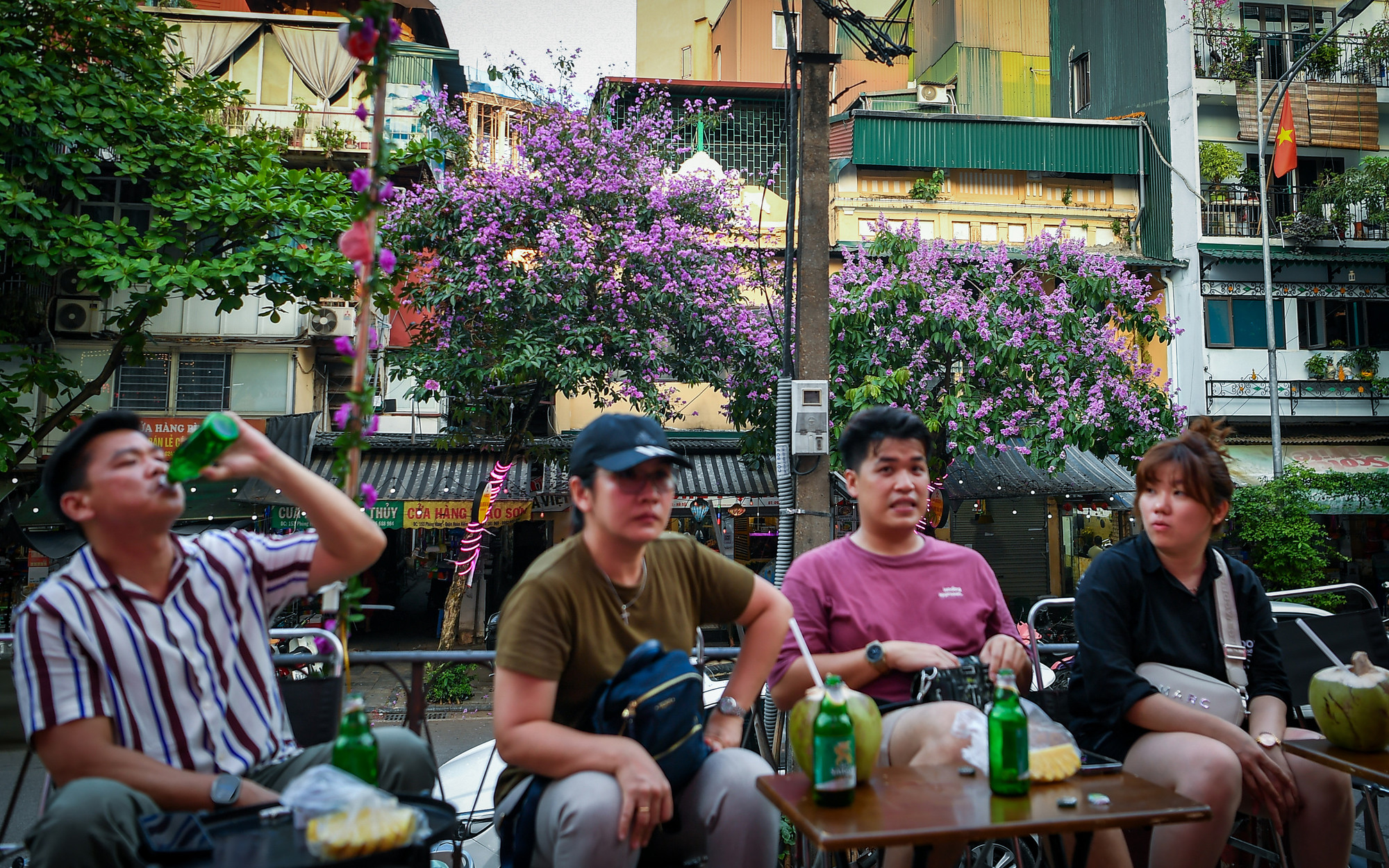 Khách du lịch "chill chill" cùng bạn bè trên phố đường tàu Phùng Hưng ngắm hoa bằng lăng.
