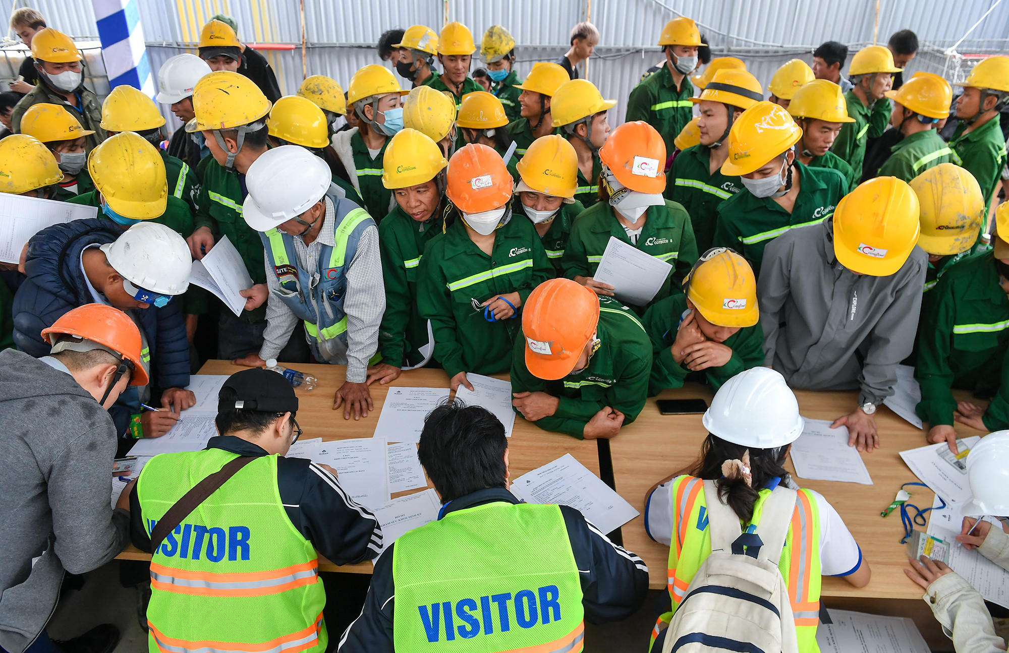 Các công nhân điền thông tin vào giấy khám sức khỏe định kỳ để chuẩn bị khám bệnh ngay trên công trường.