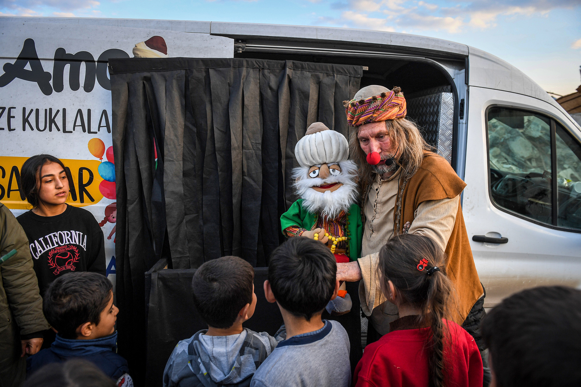 Trong trang phục chú hề với cái mũi đỏ chót và con rối khổng lồ trên tay, ông bắt đầu cất tiếng gọi: “Các bạn nhỏ có muốn xem ảo thuật và nghe chuyện cổ tích không nào?”