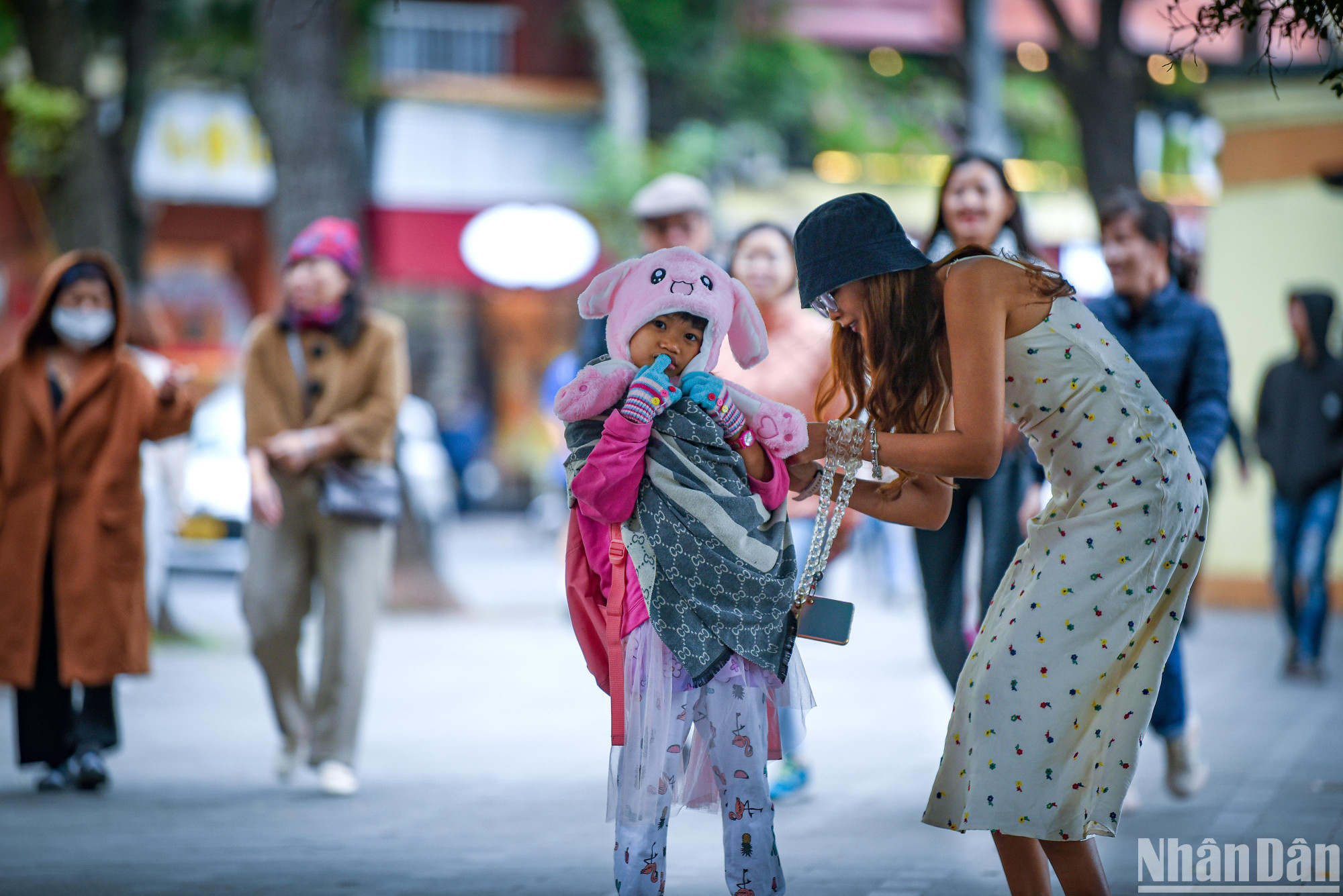 Do thời tiết lạnh đột ngột nhiều người phụ huynh đã lấy cả khăn để trùm lên người con em mình để tránh lạnh. (Ảnh: THÀNH ĐẠT)