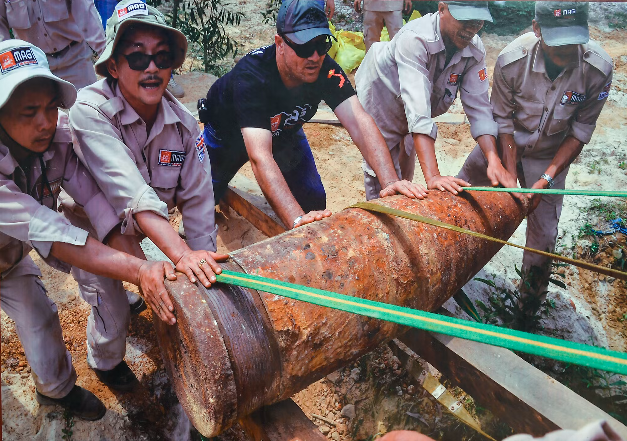 Kỹ thuật viên MAG nỗ lực di chuyển một trong hai quả đạn pháo nặng gần 900kg được phát hiện tại thôn Thuỷ Khê, huyện Gio Linh lên xe tải đến bãi huỷ nổ tập trung (Ảnh chụp tháng 4 năm 2016).
